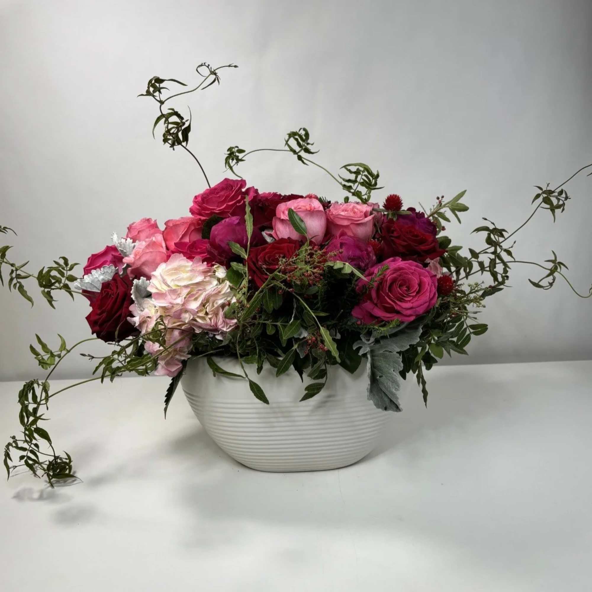 Mixed pink and red roses arranged in a white bowl vase