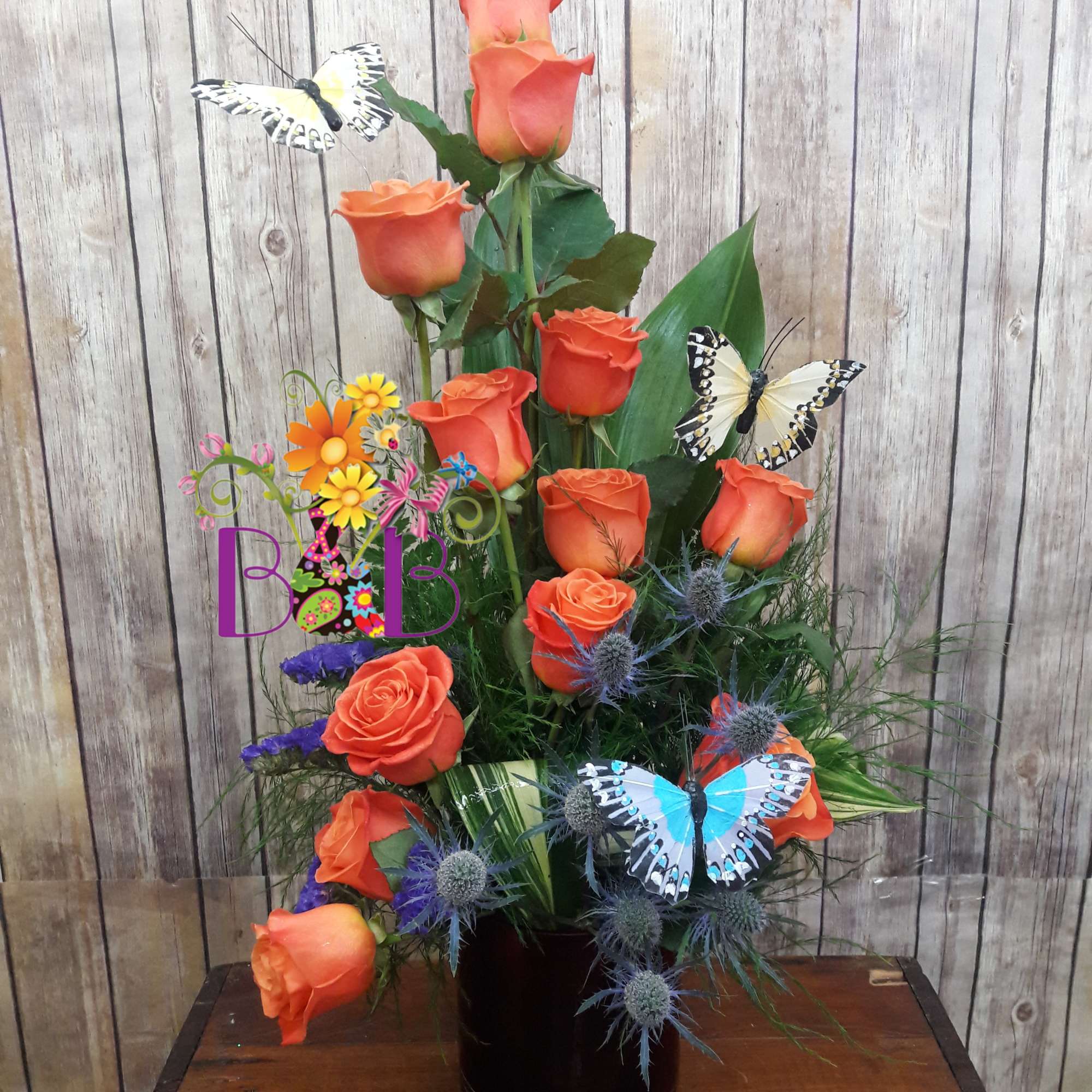 Orange roses arranged in a black vase with decorative butterflies
