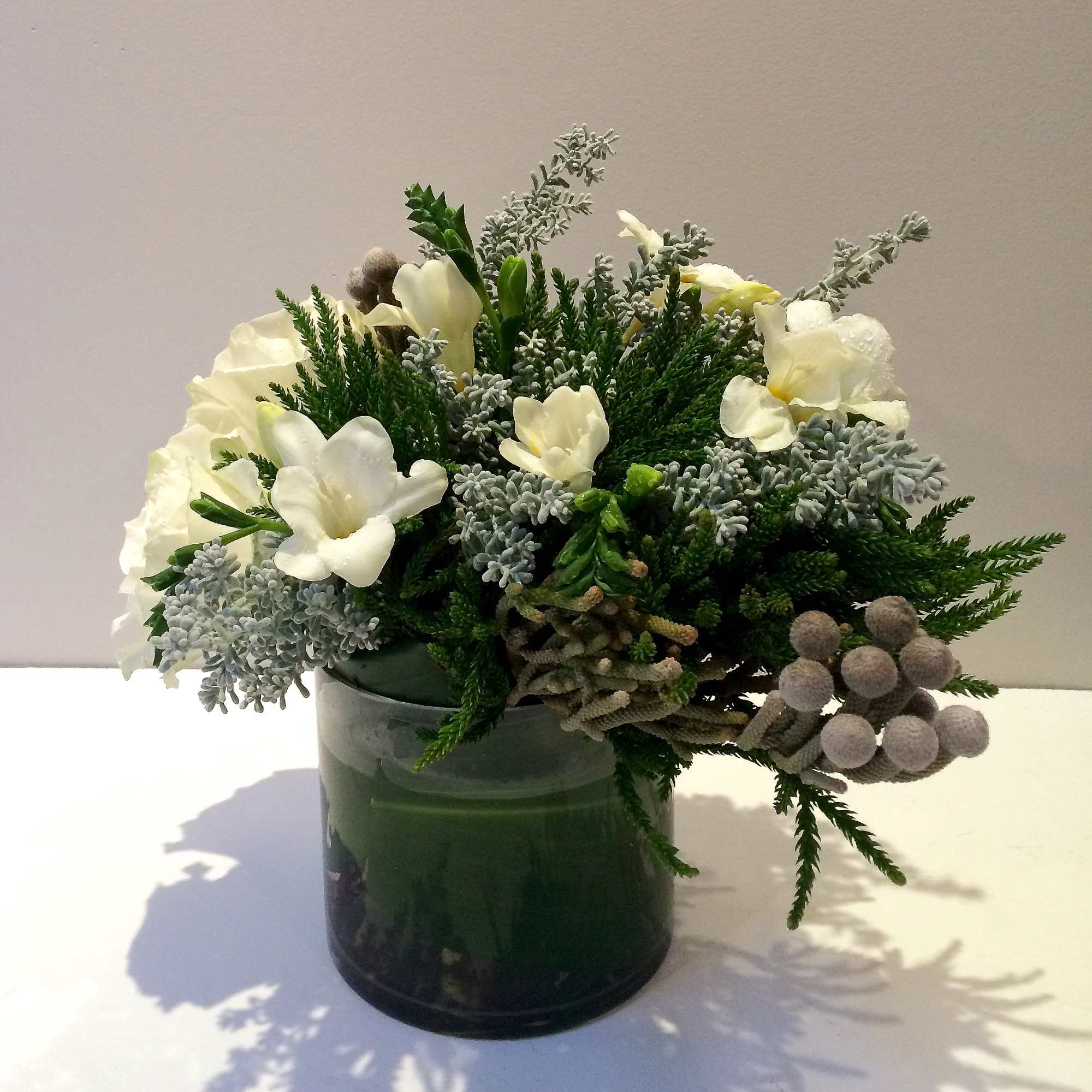 White flowers and greenery arranged in a dark glass vase
