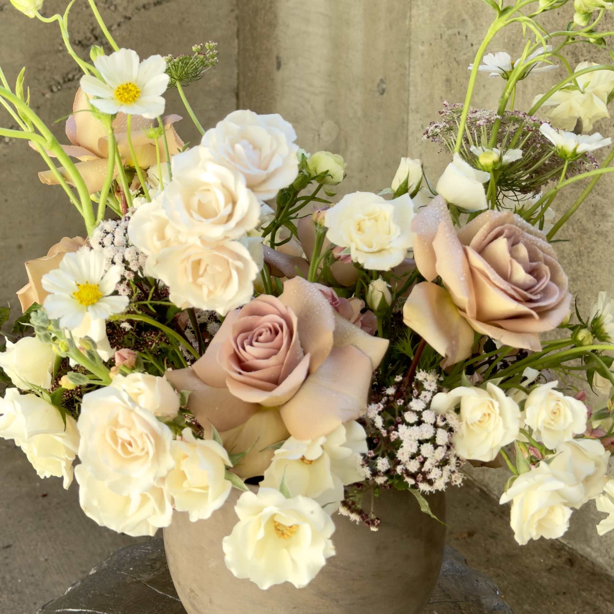 Cream and blush roses with white daisies in a beige vase
