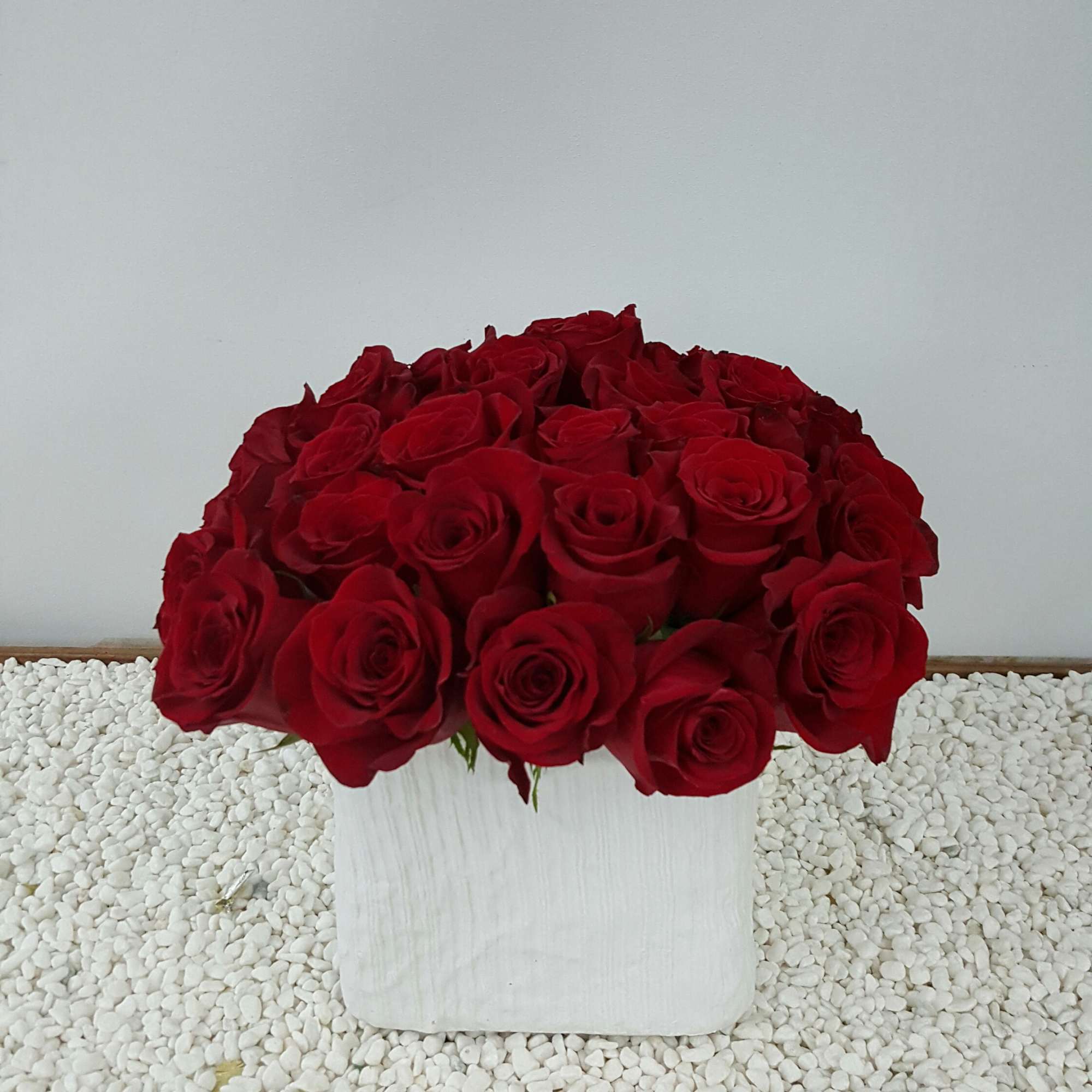 Bouquet of red roses in a white square vase