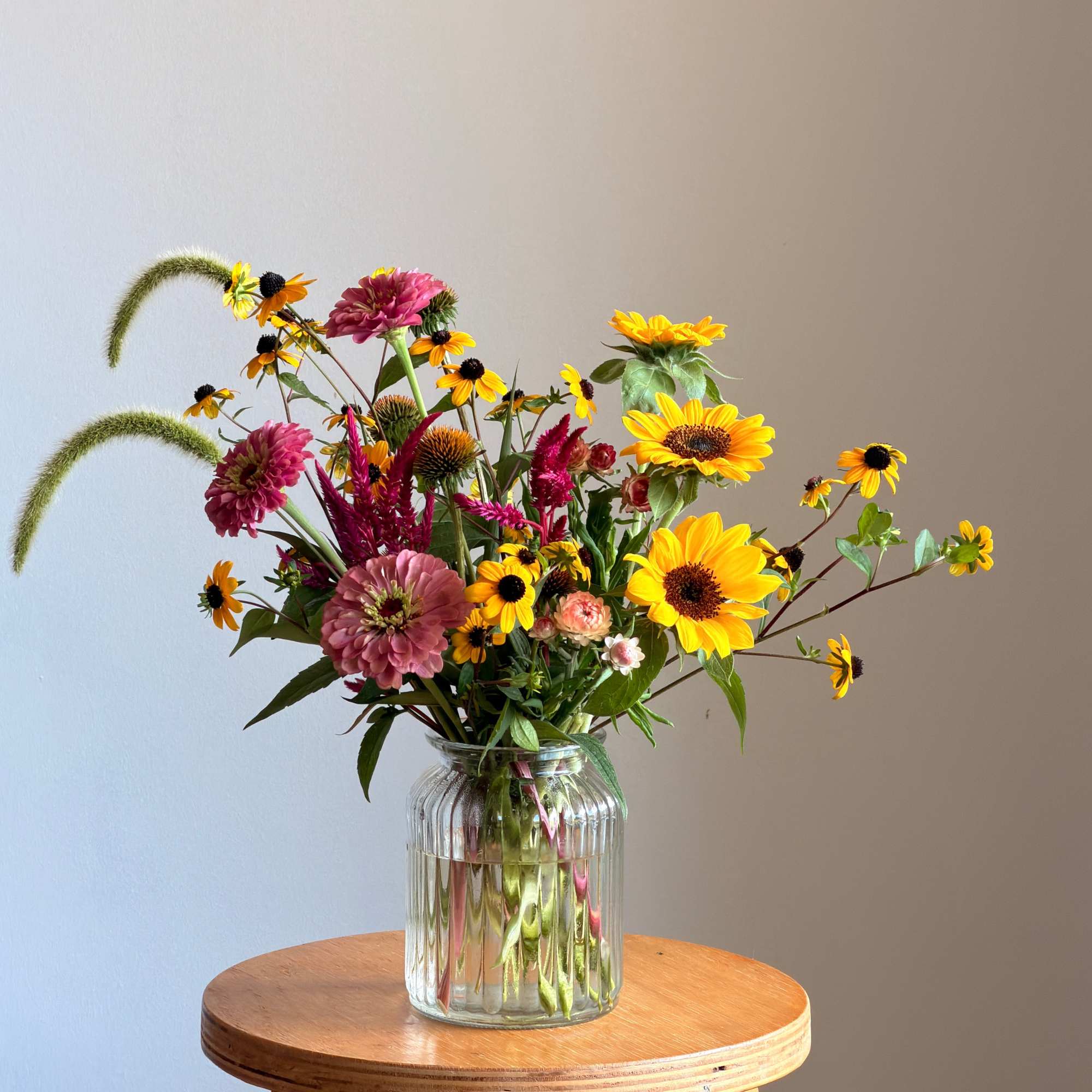 Mixed bouquet of yellow and pink flowers in a clear glass vase