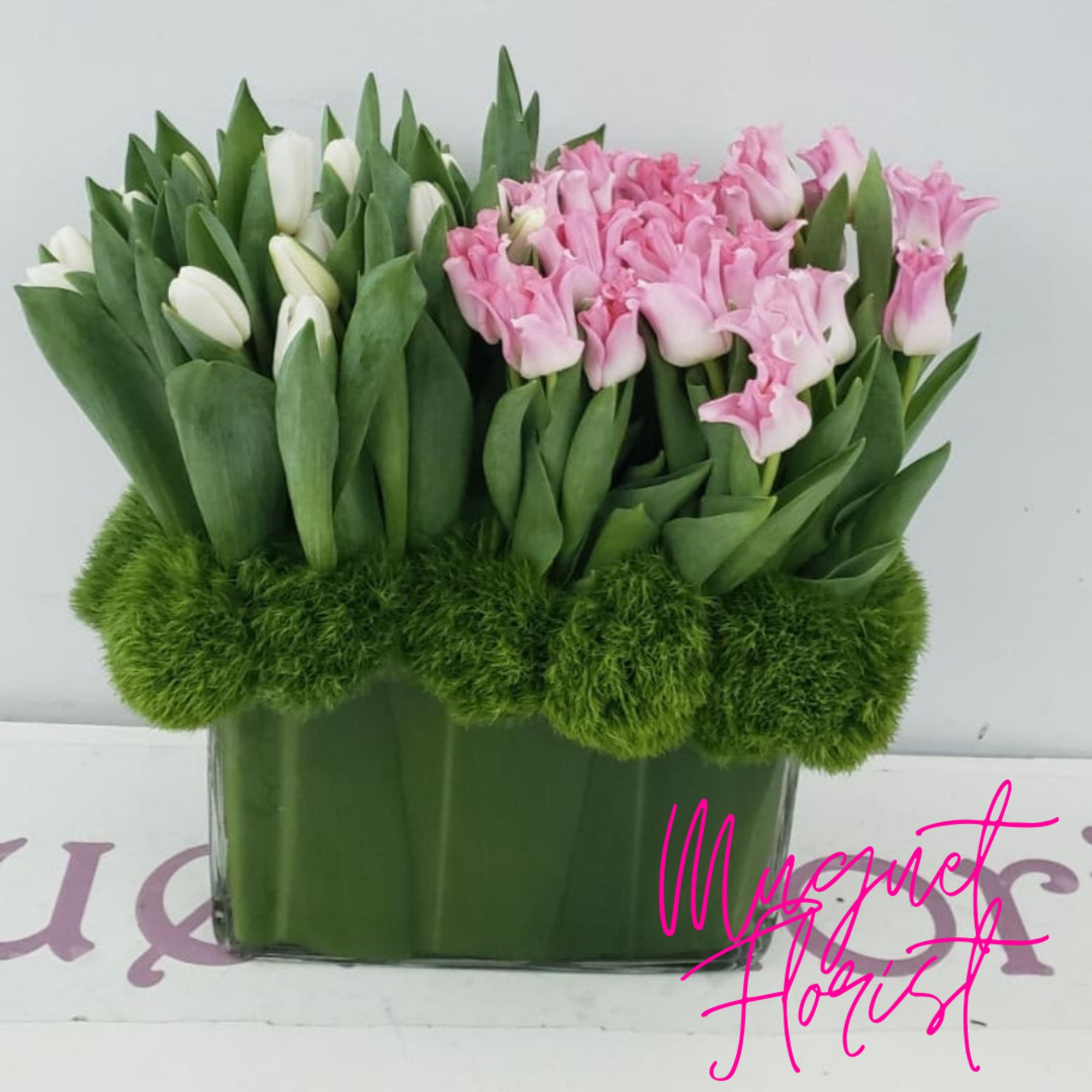 Pink and white tulips arranged in a rectangular glass vase
