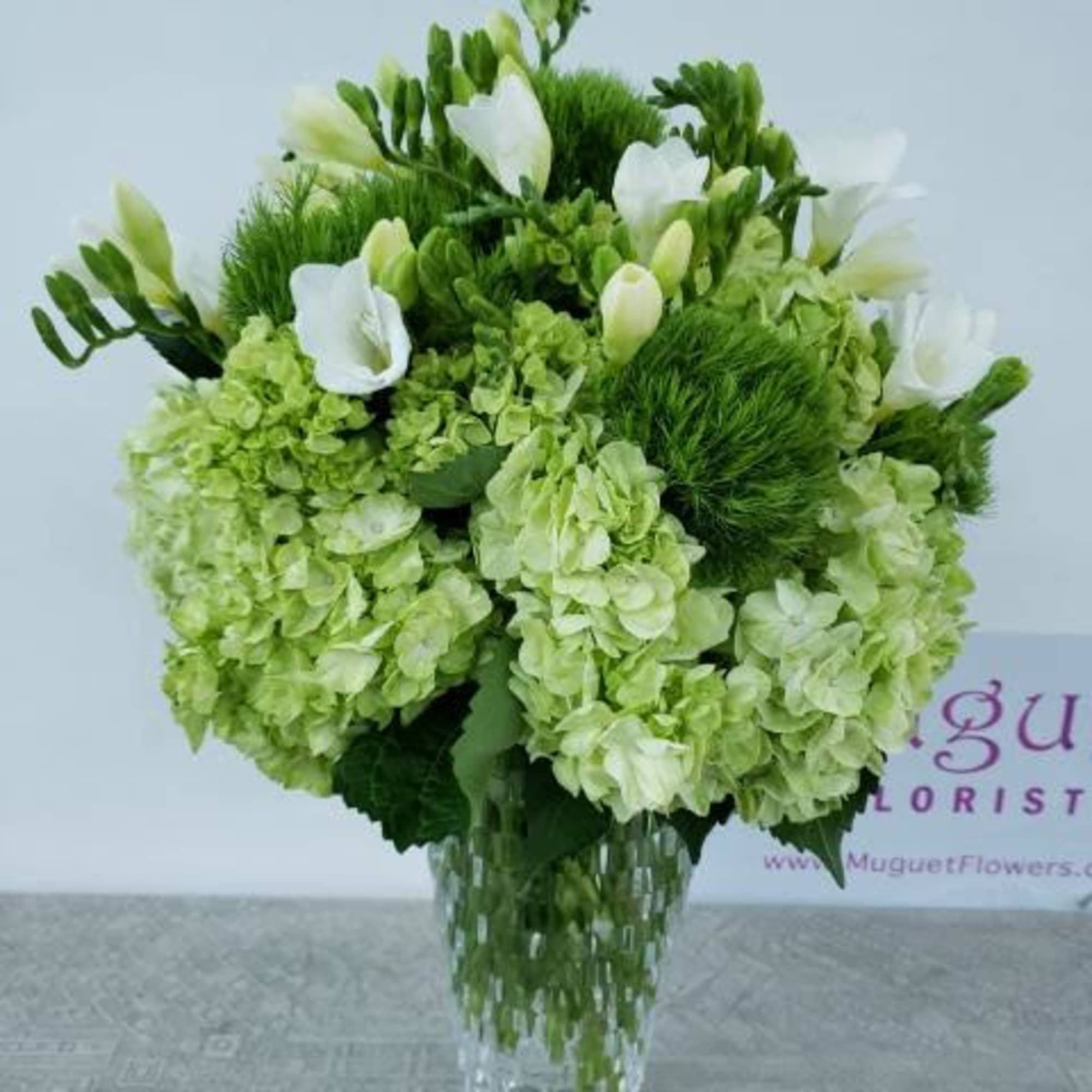 Green and white floral arrangement in a clear glass vase, photo 2 of 4