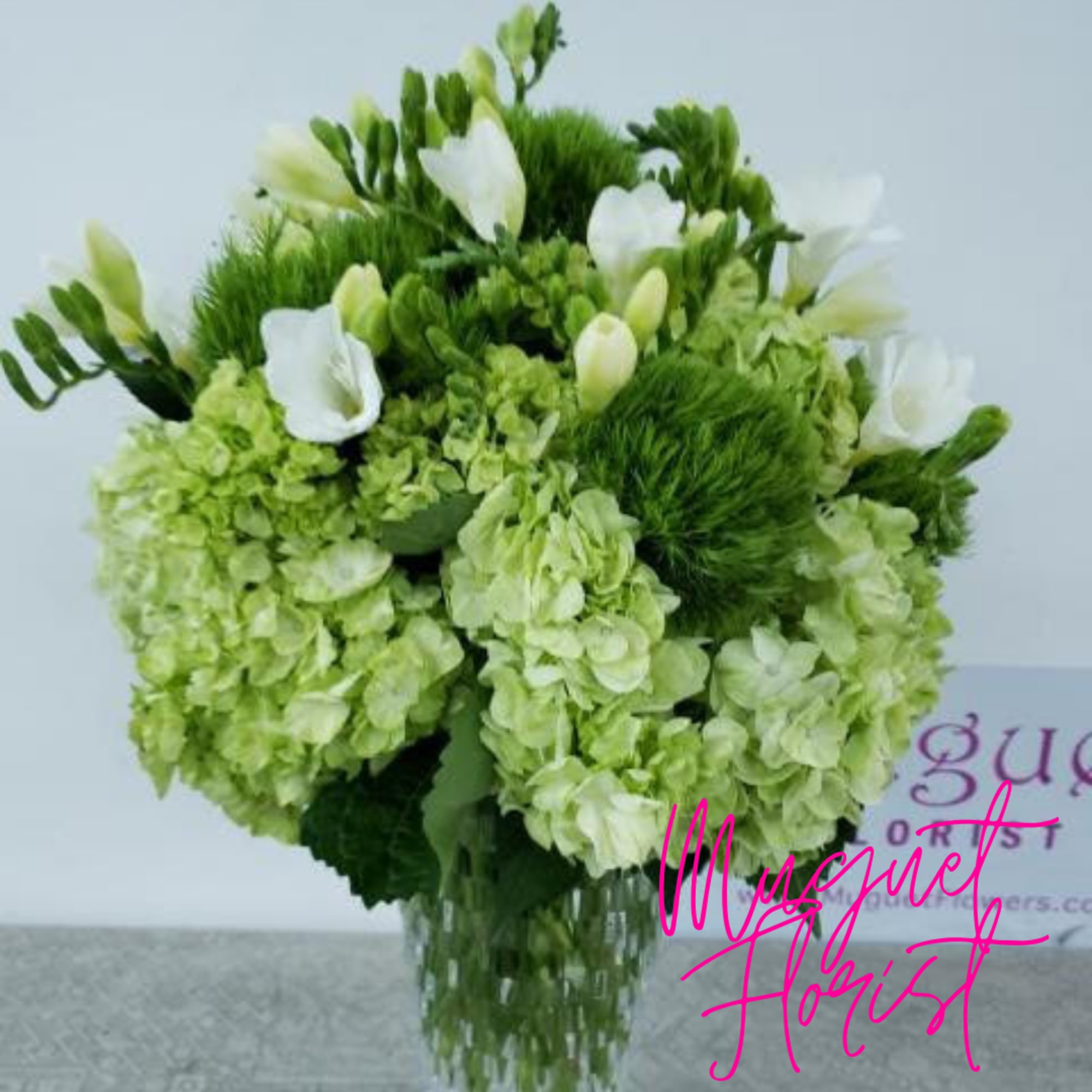 Green and white floral arrangement in a clear glass vase, photo 3 of 4