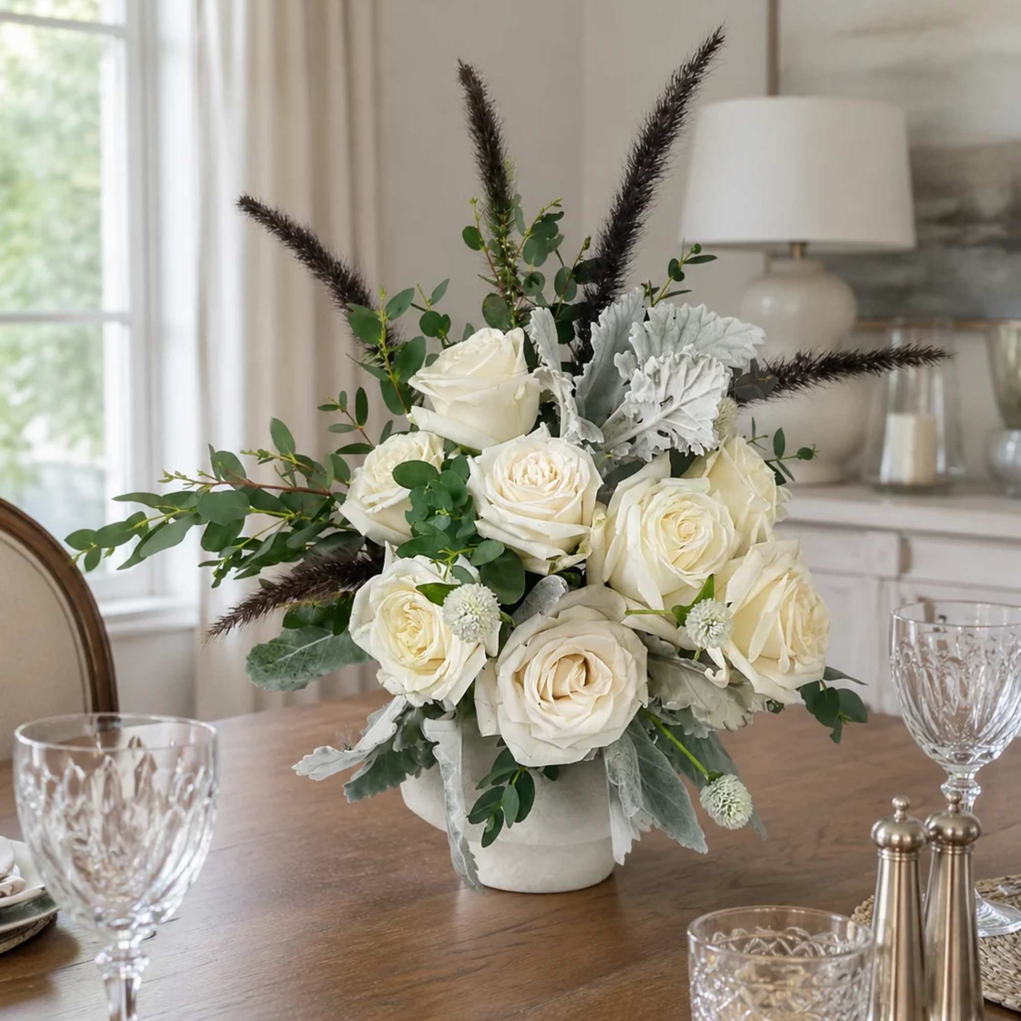 White rose arrangement in a low vase with greenery and dark feathery accents