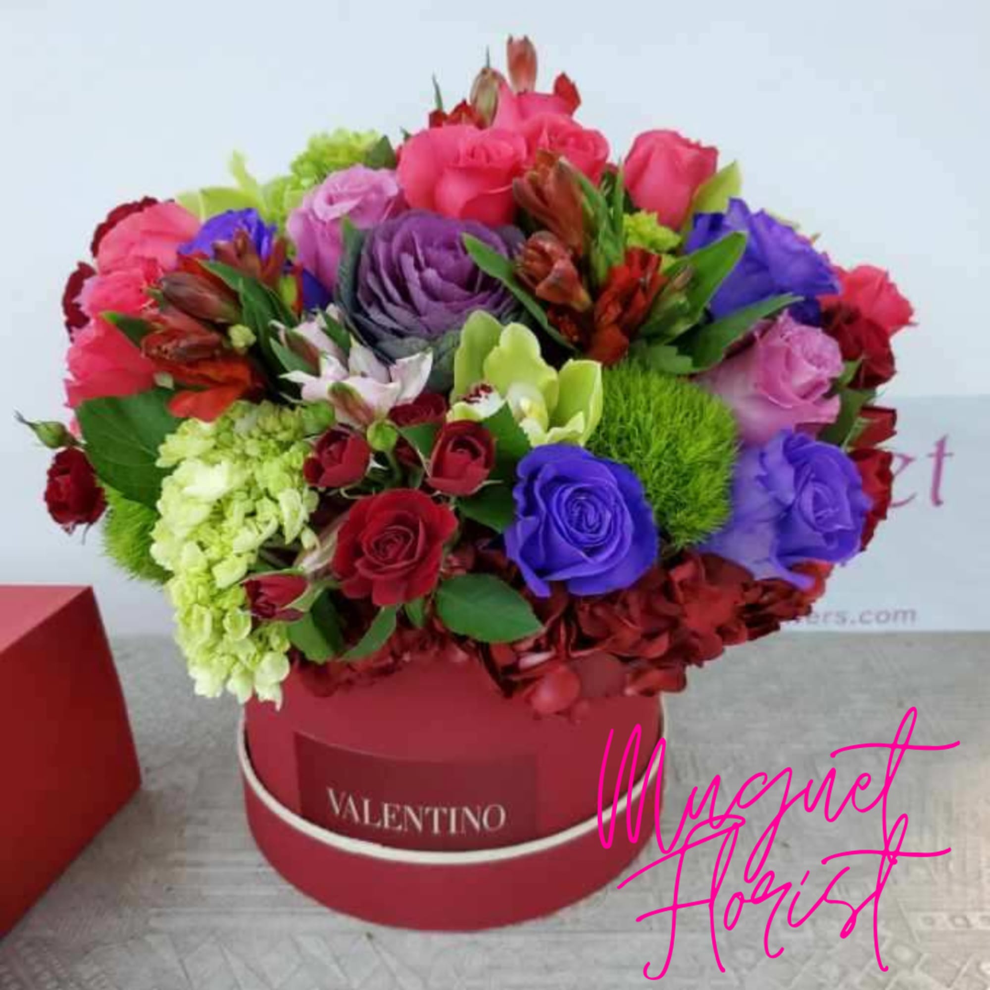Colorful bouquet of roses and mixed flowers in a red hat box