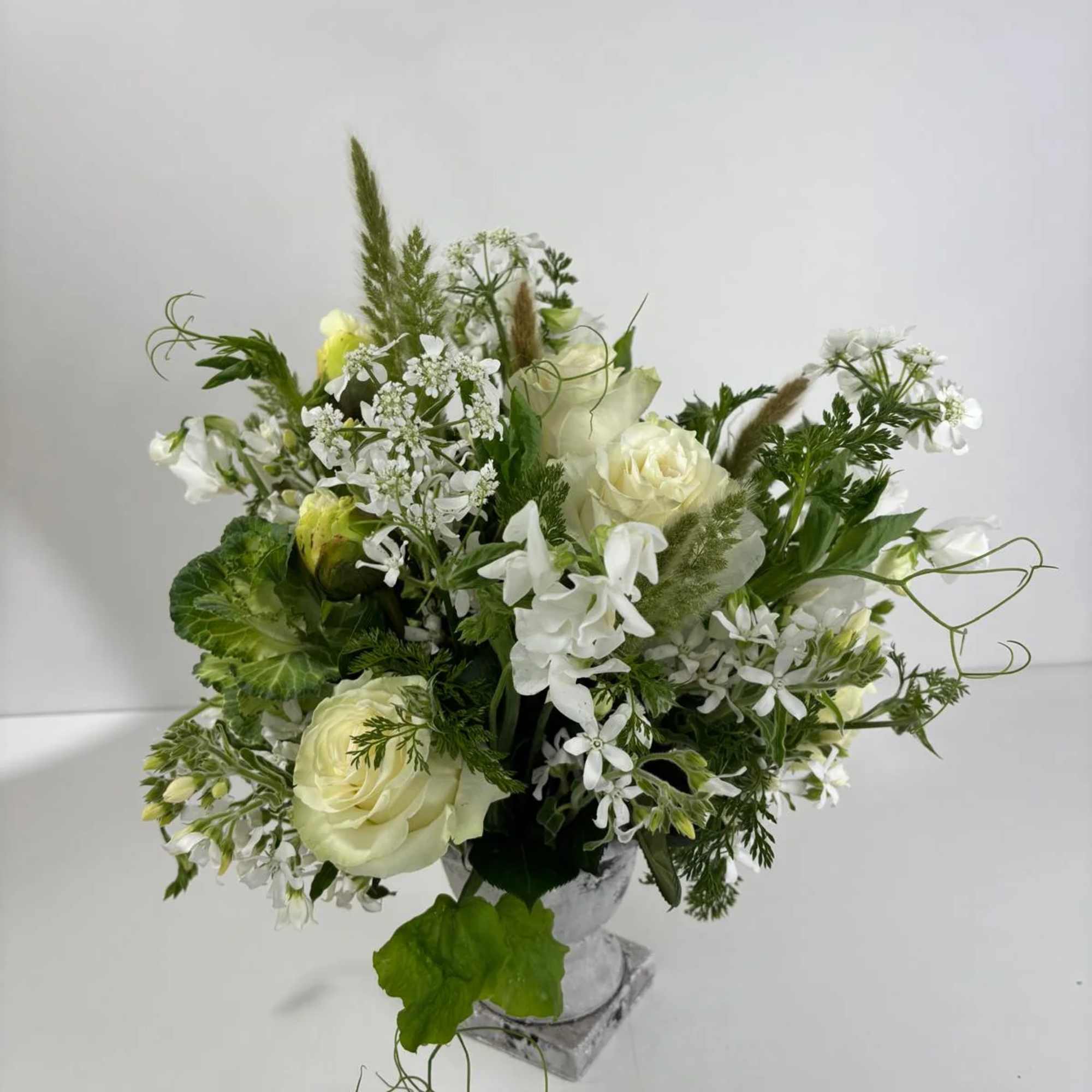 White and pale green floral arrangement in a clear vase