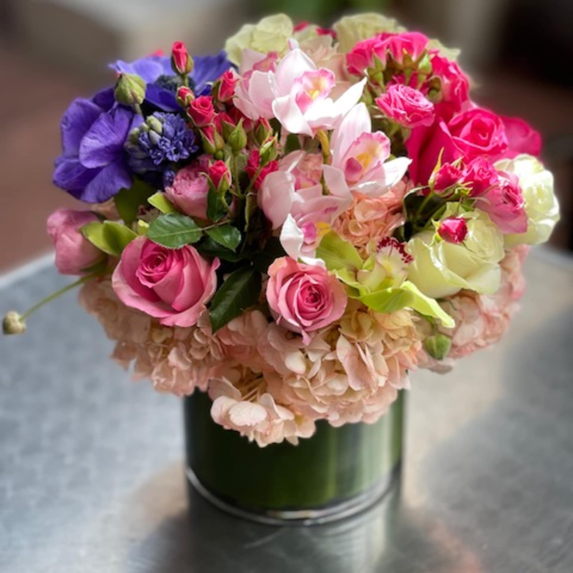 Mixed bouquet of pink, purple, and cream flowers in a glass vase
