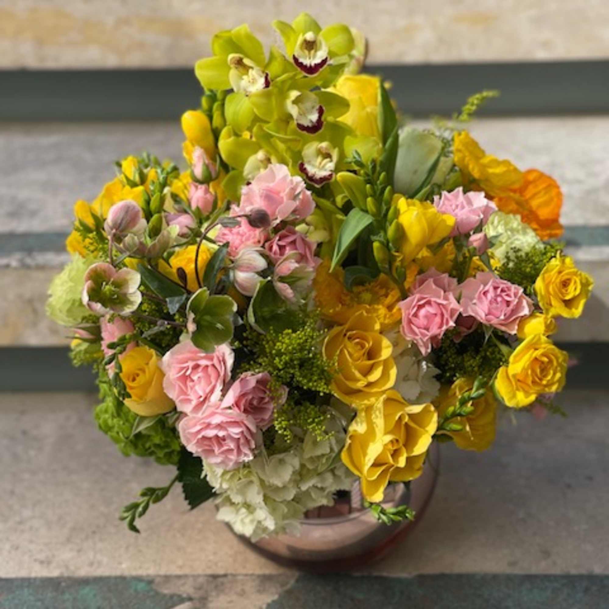 Bouquet of yellow orchids, pink roses, and green hydrangeas in a vase