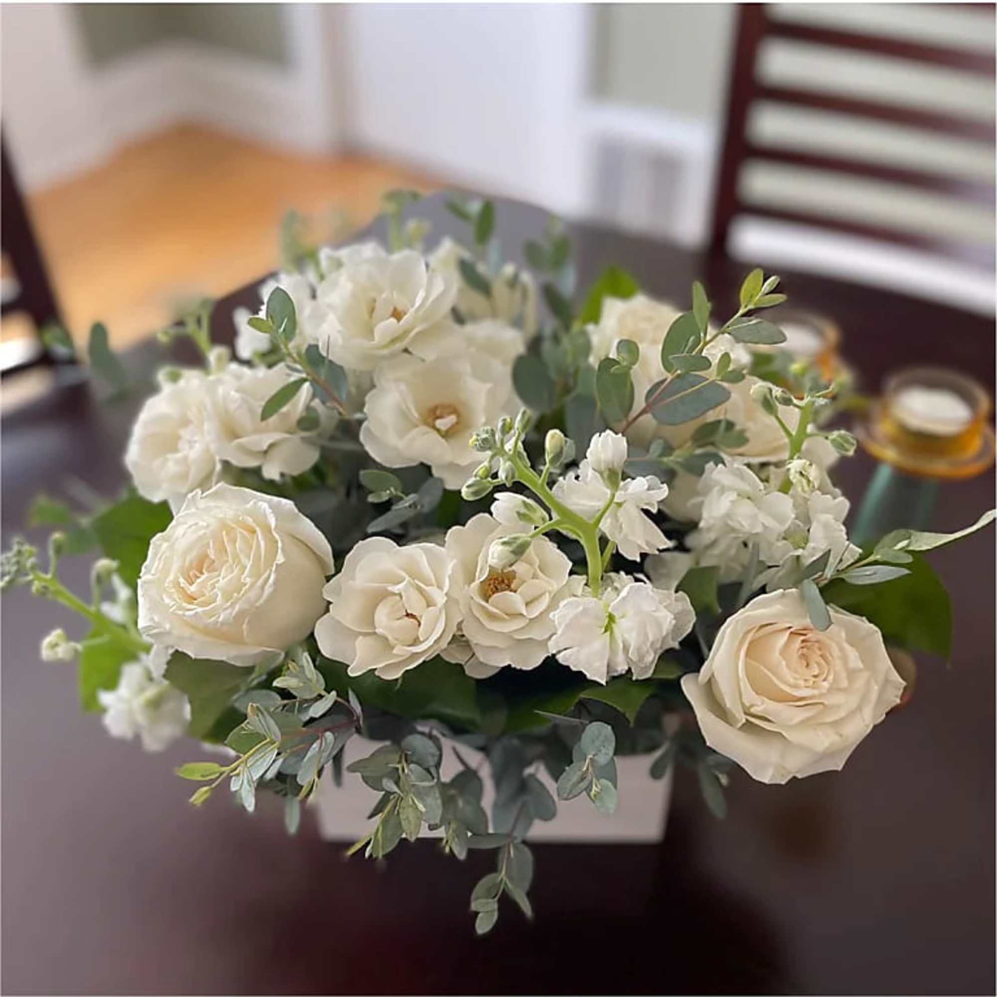 White roses and small white blooms arranged in a square vase