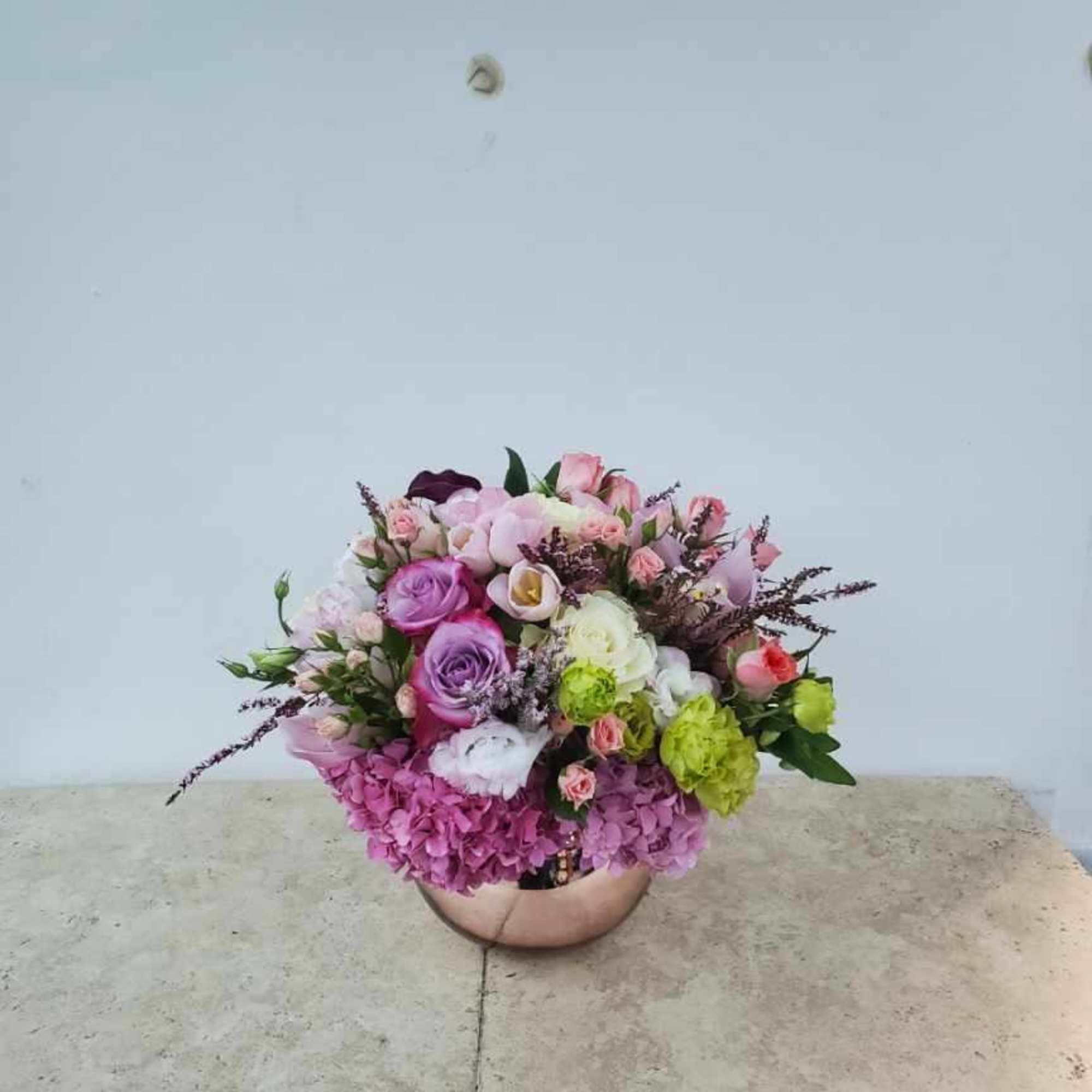 Mixed pink and purple flower arrangement in a round vase