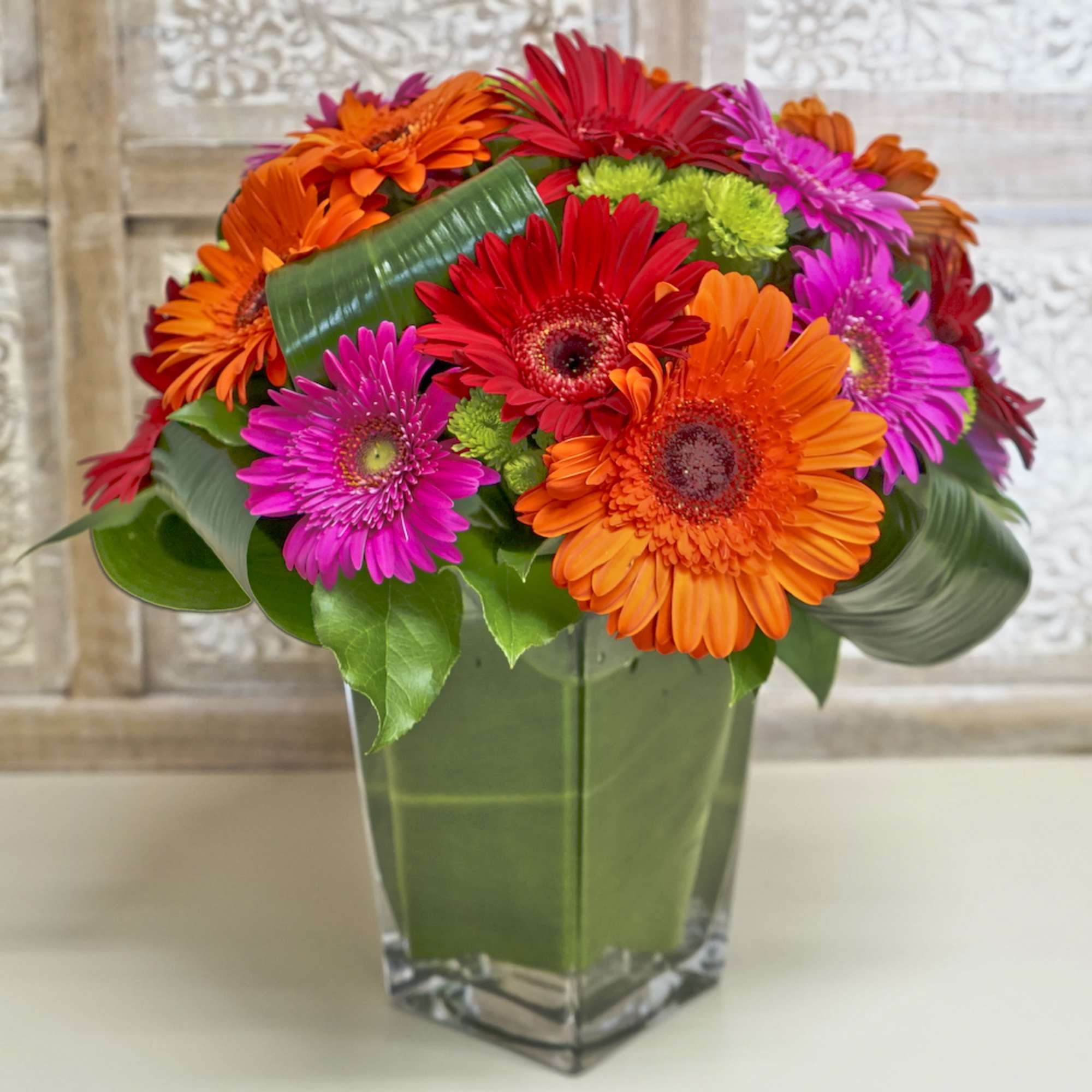 Bright gerbera daisy bouquet in a square glass vase