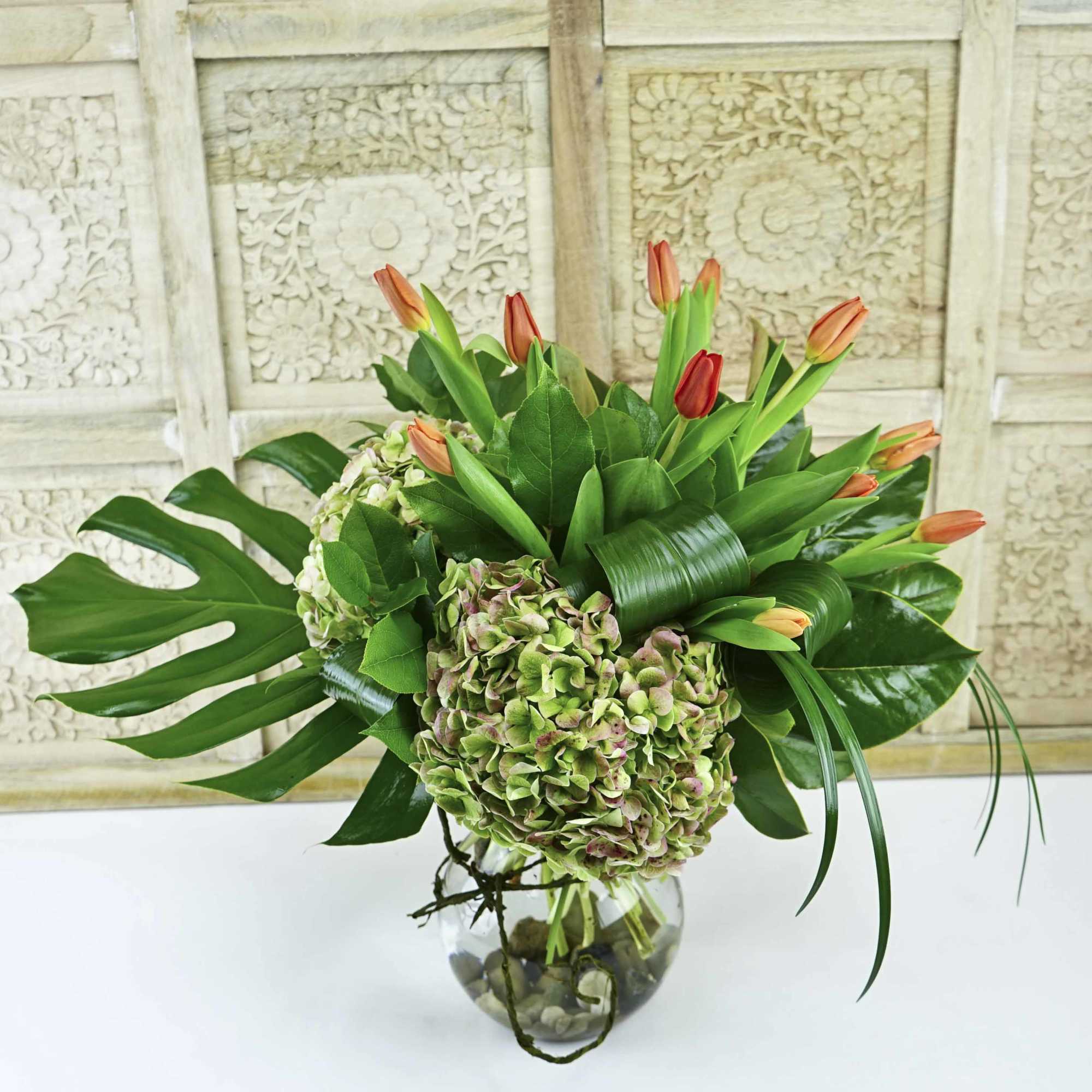 Bouquet of orange tulips and green hydrangeas in a glass vase
