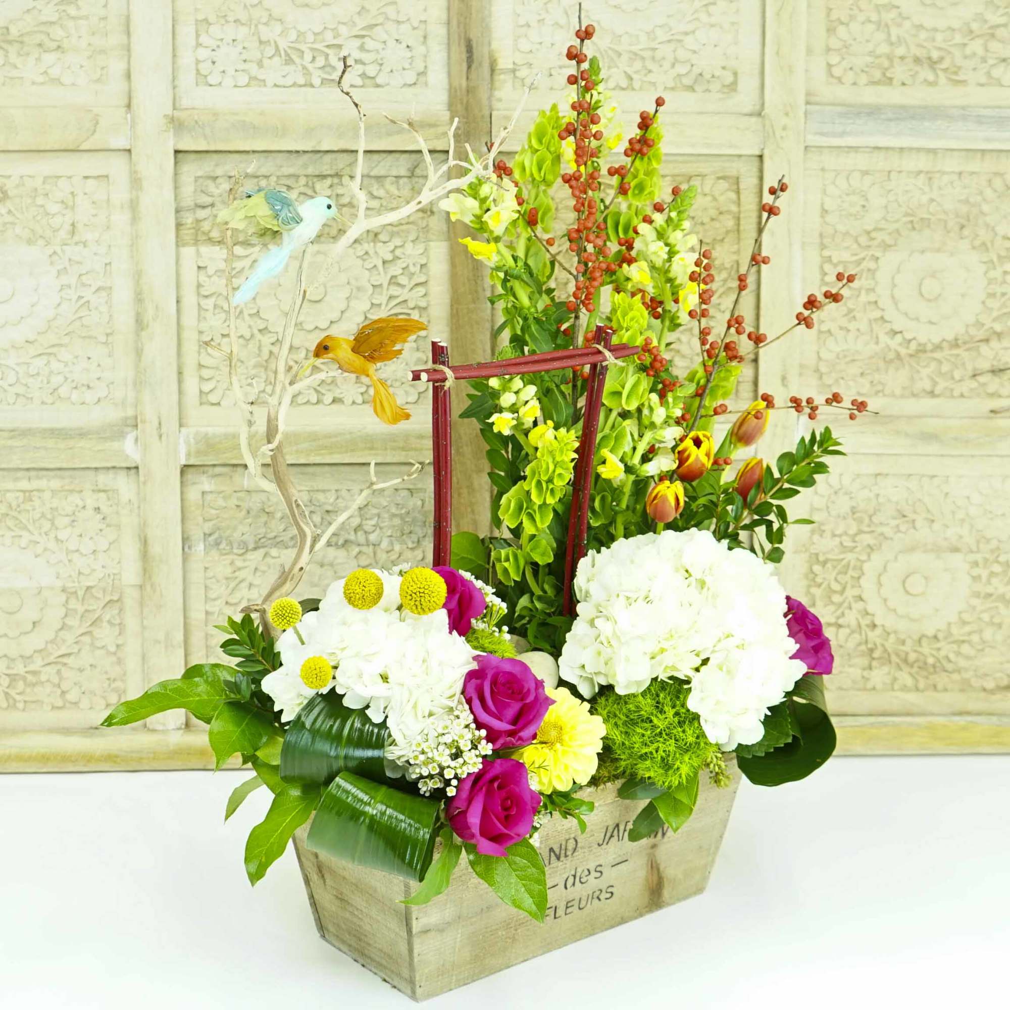 Mixed floral arrangement in a wooden box with decorative bird picks