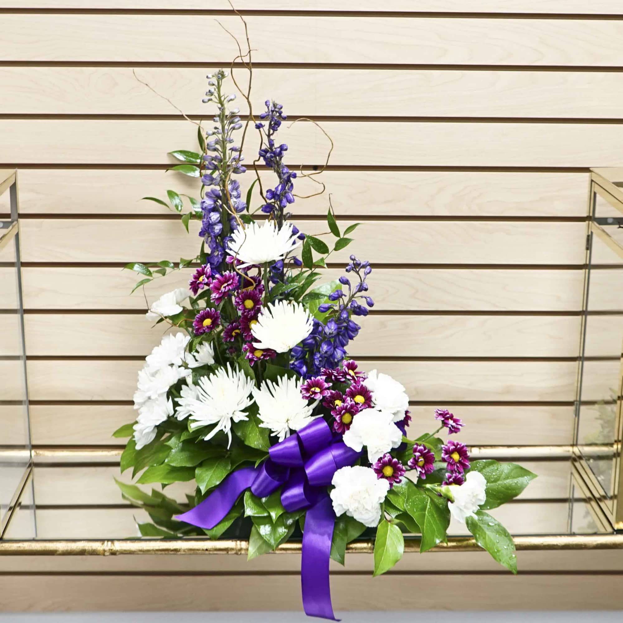 Tall floral arrangement with white and purple flowers and a purple ribbon