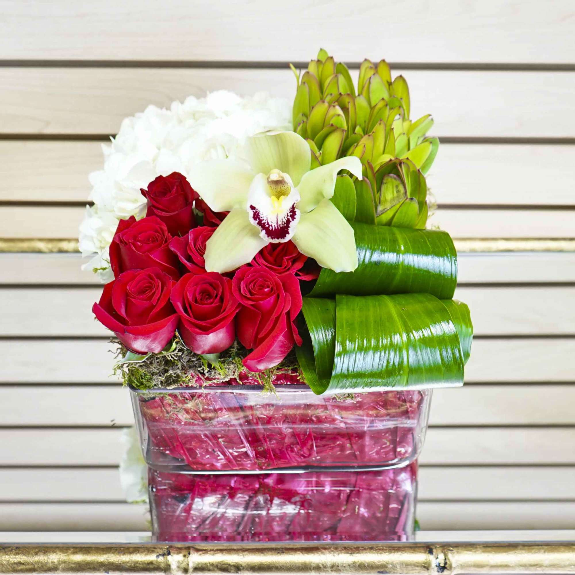 Red roses and white orchids in a clear square vase