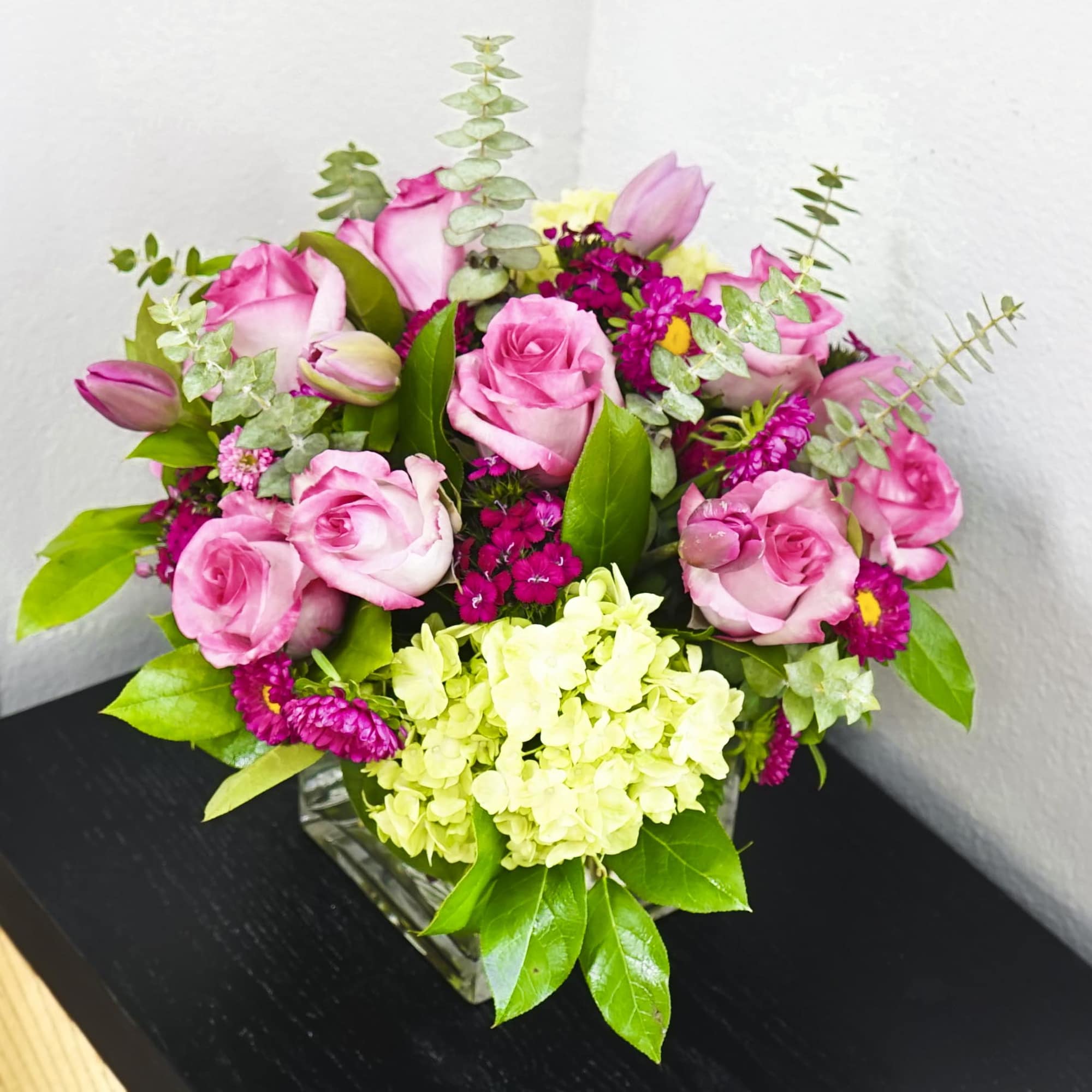 Pink roses and green hydrangeas in a square glass vase