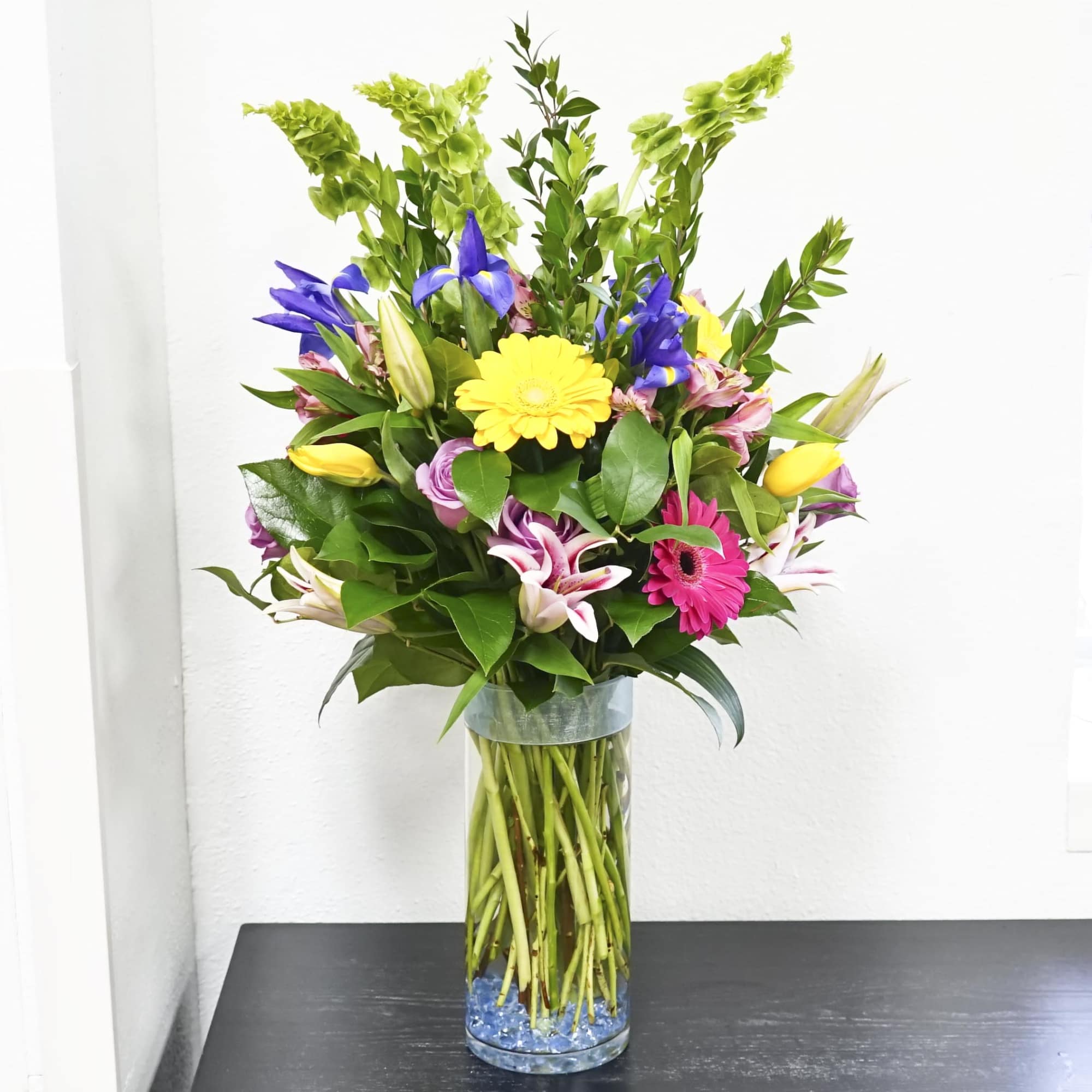 Mixed bouquet with lilies, gerbera daisies, and tulips in a glass vase