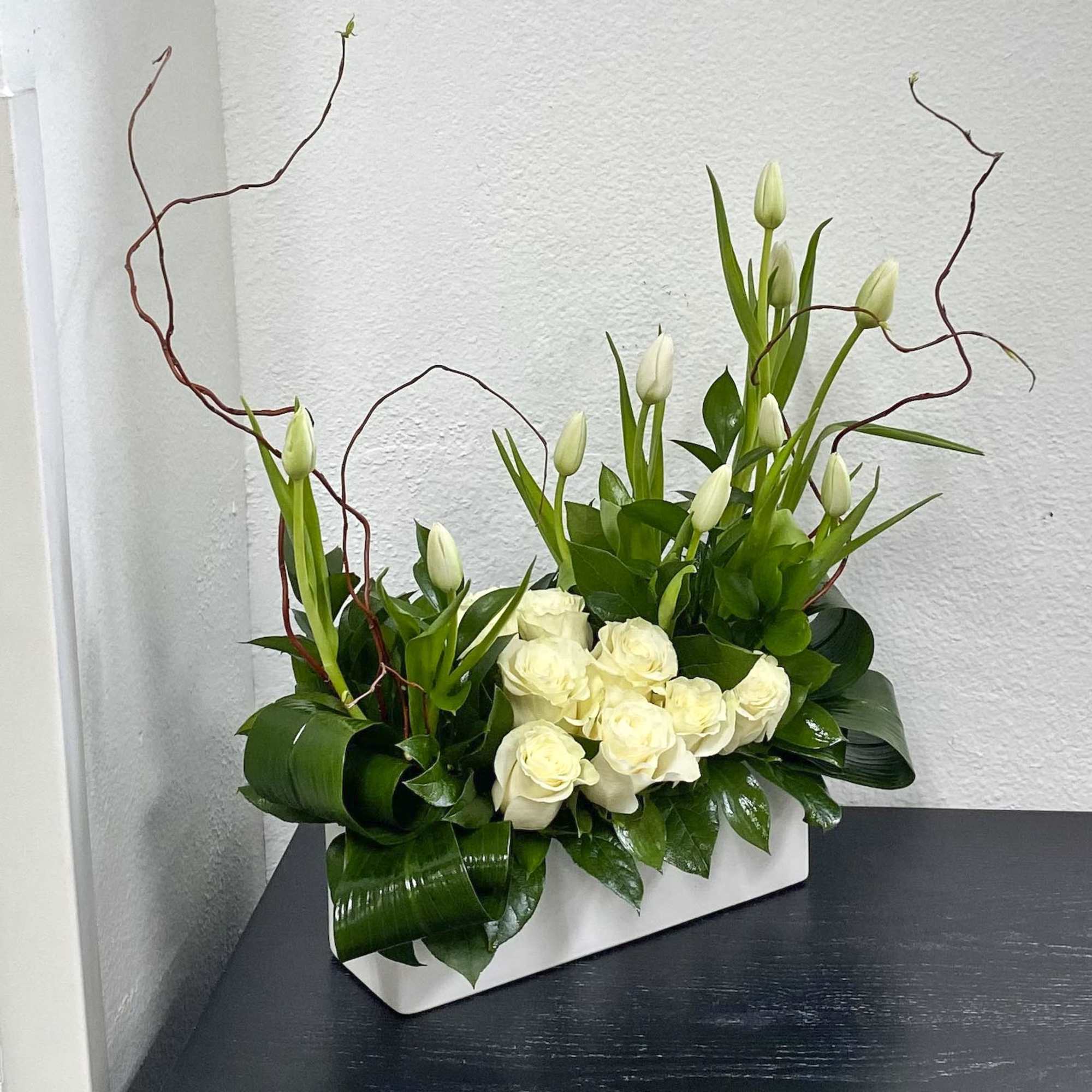 White roses and tulip buds in a rectangular white container