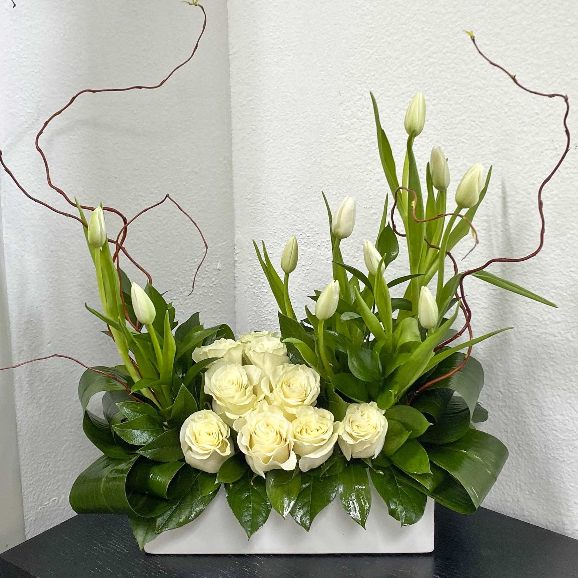 White roses and tulip buds arranged in a white rectangular container