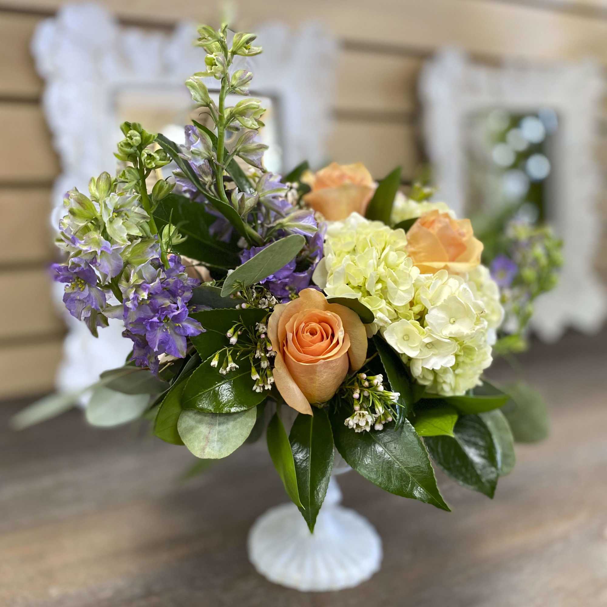 Peach roses and pale hydrangeas in a white pedestal vase, photo 2 of 3