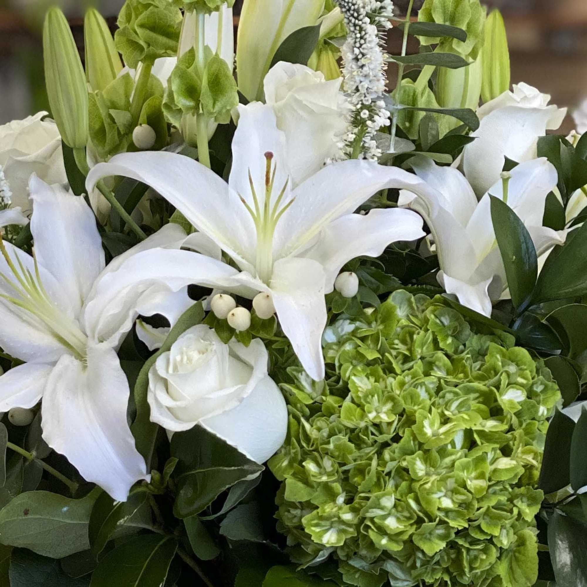 White lilies and roses with green hydrangeas in a floral arrangement