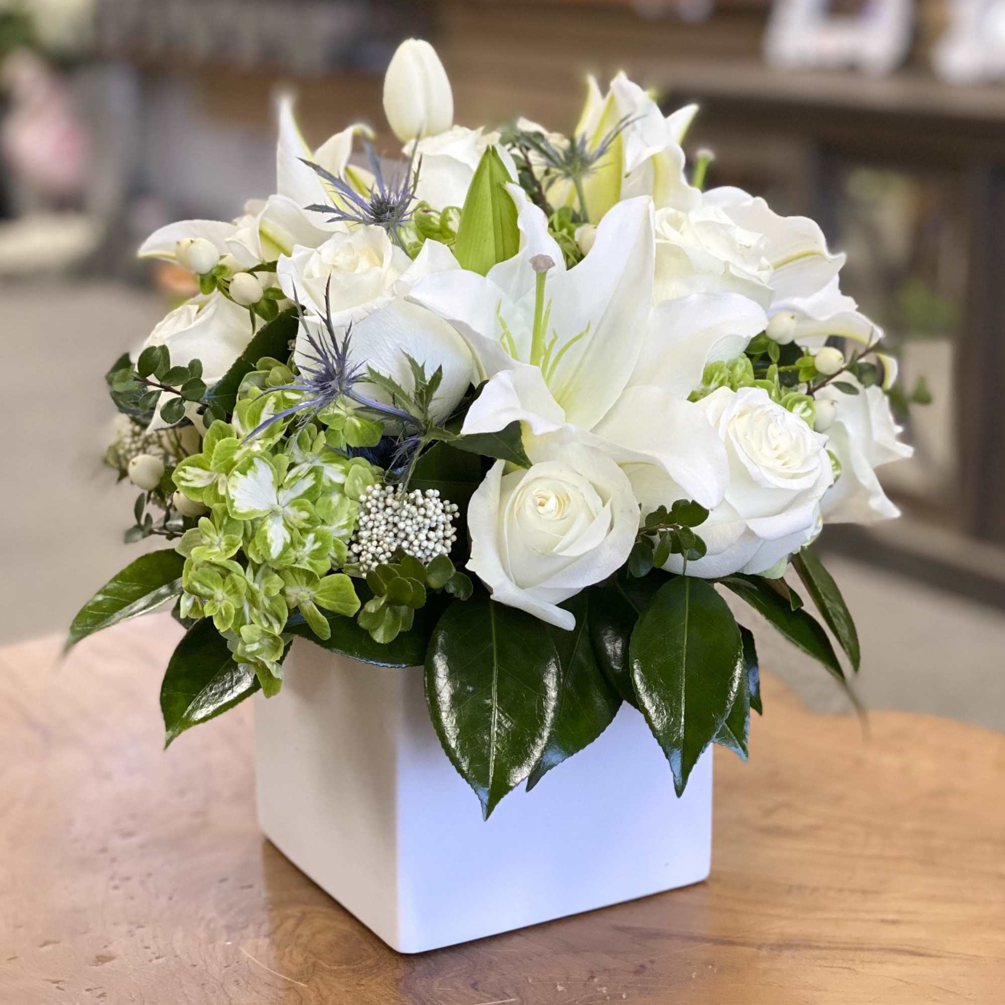 White roses and lilies arranged in a square white vase