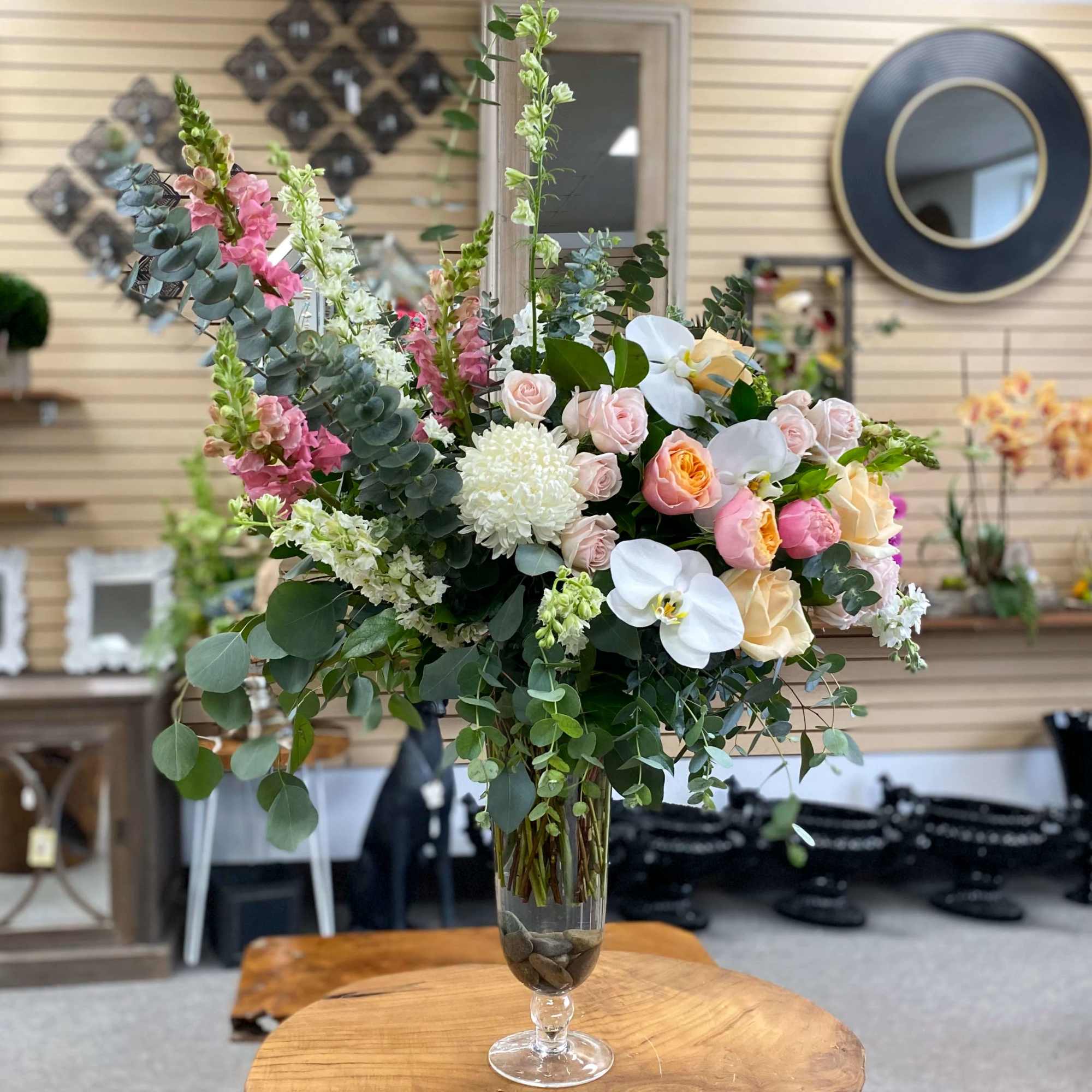 Tall floral arrangement in a clear glass vase with pink, white, and peach blooms