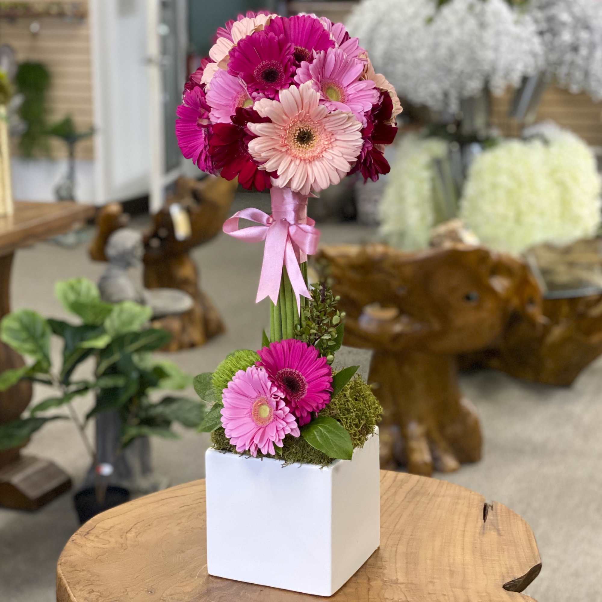 Pink gerbera daisy arrangement in a white cube vase with a ribbon