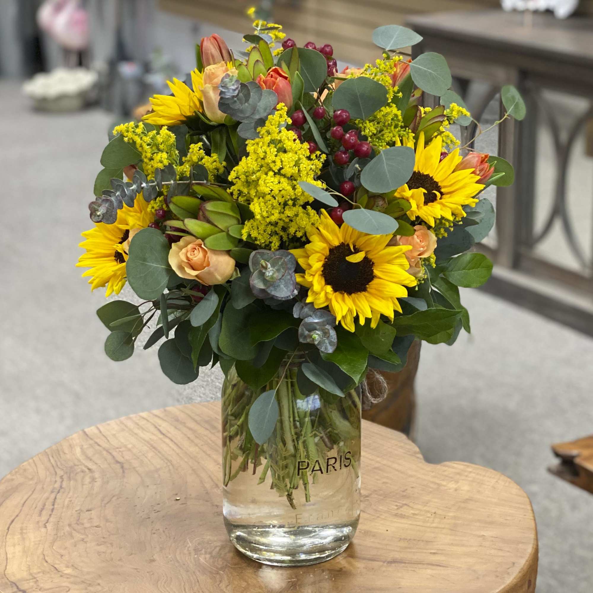 Bouquet of sunflowers and peach roses in a clear glass vase