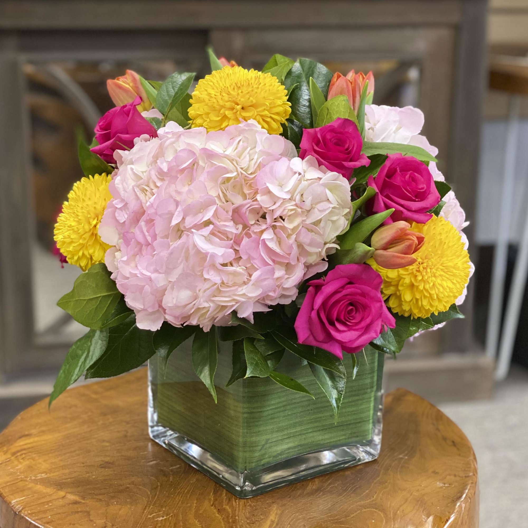 Pink hydrangea and roses in a square glass vase with yellow blooms