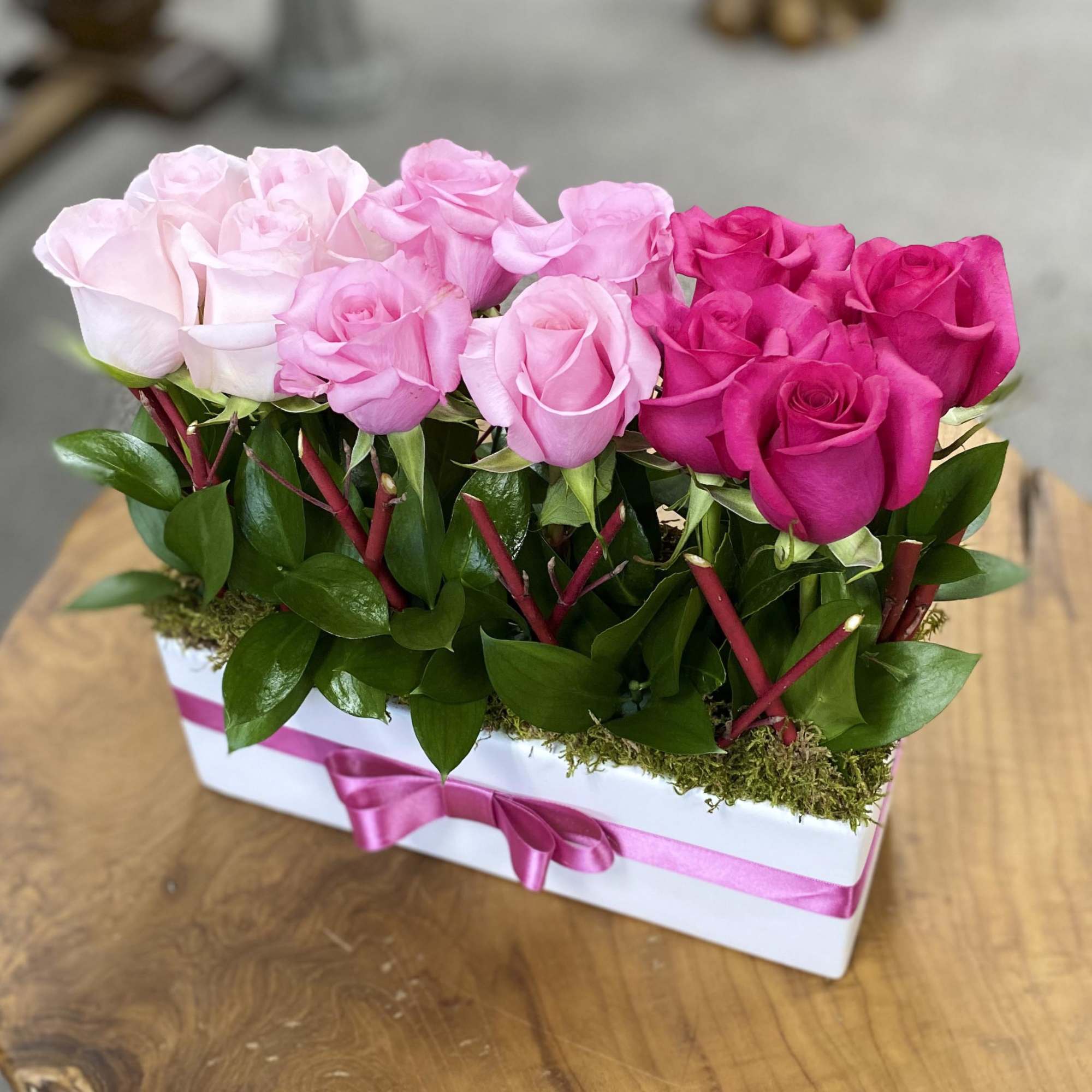 Pink and hot pink roses arranged in a white box with a ribbon