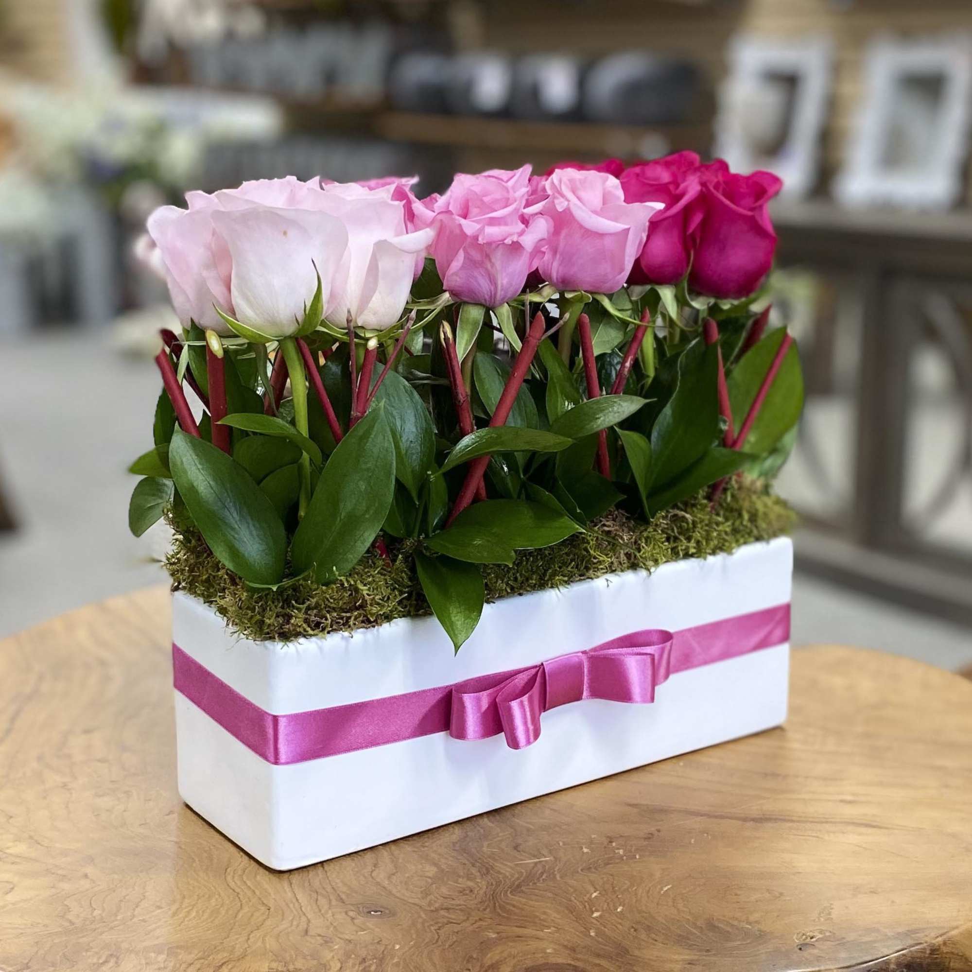 Pink roses arranged in a white box with a pink ribbon