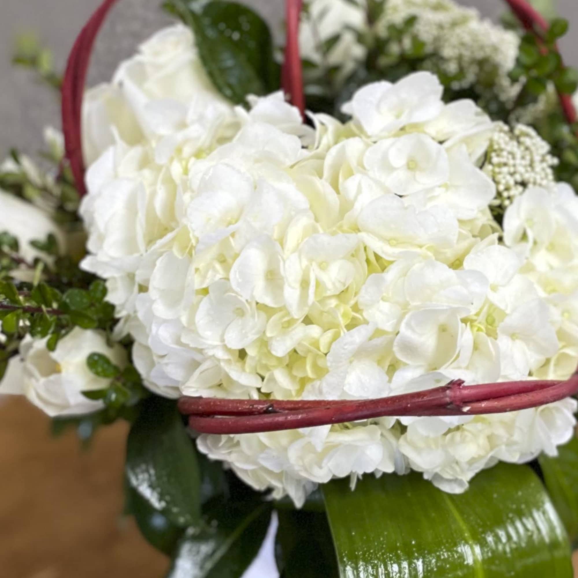 White hydrangea bouquet with red basket handles