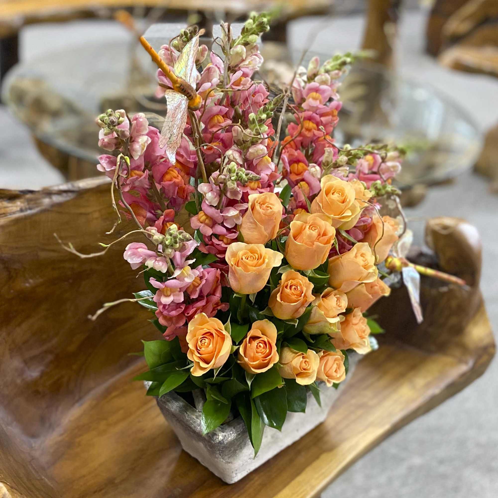 Orange roses and pink snapdragons in a square vase