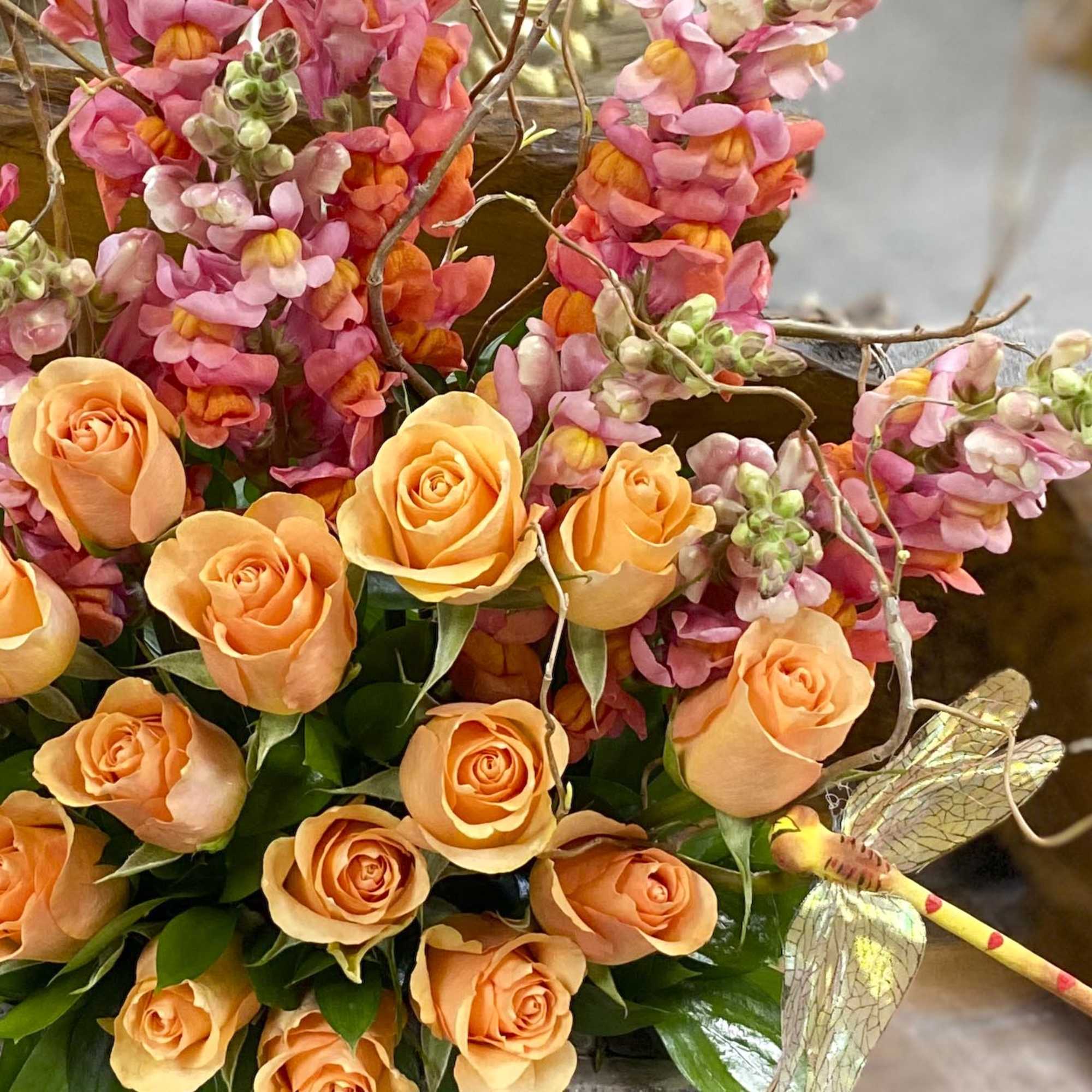 Orange roses with pink snapdragons and a dragonfly decoration