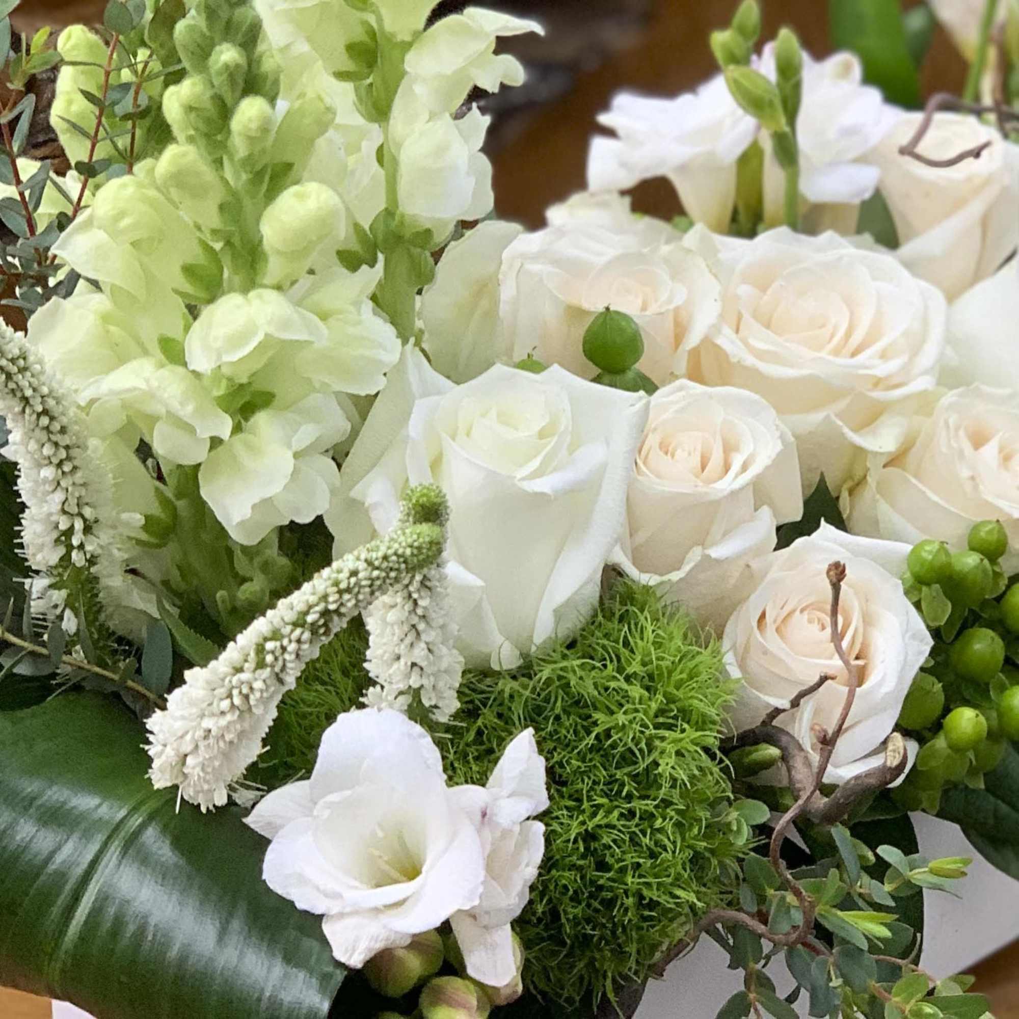White roses and pale green flowers arranged with greenery.