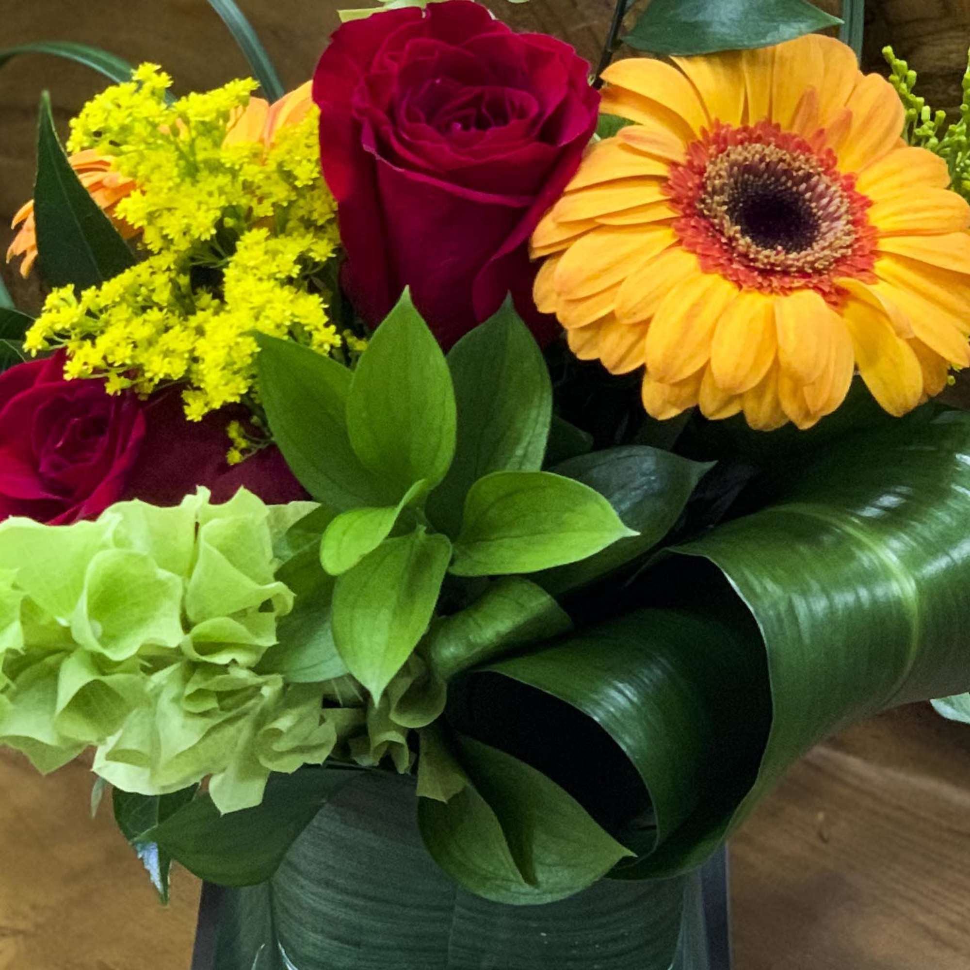 Bouquet of red roses, orange gerbera daisies, and green hydrangea