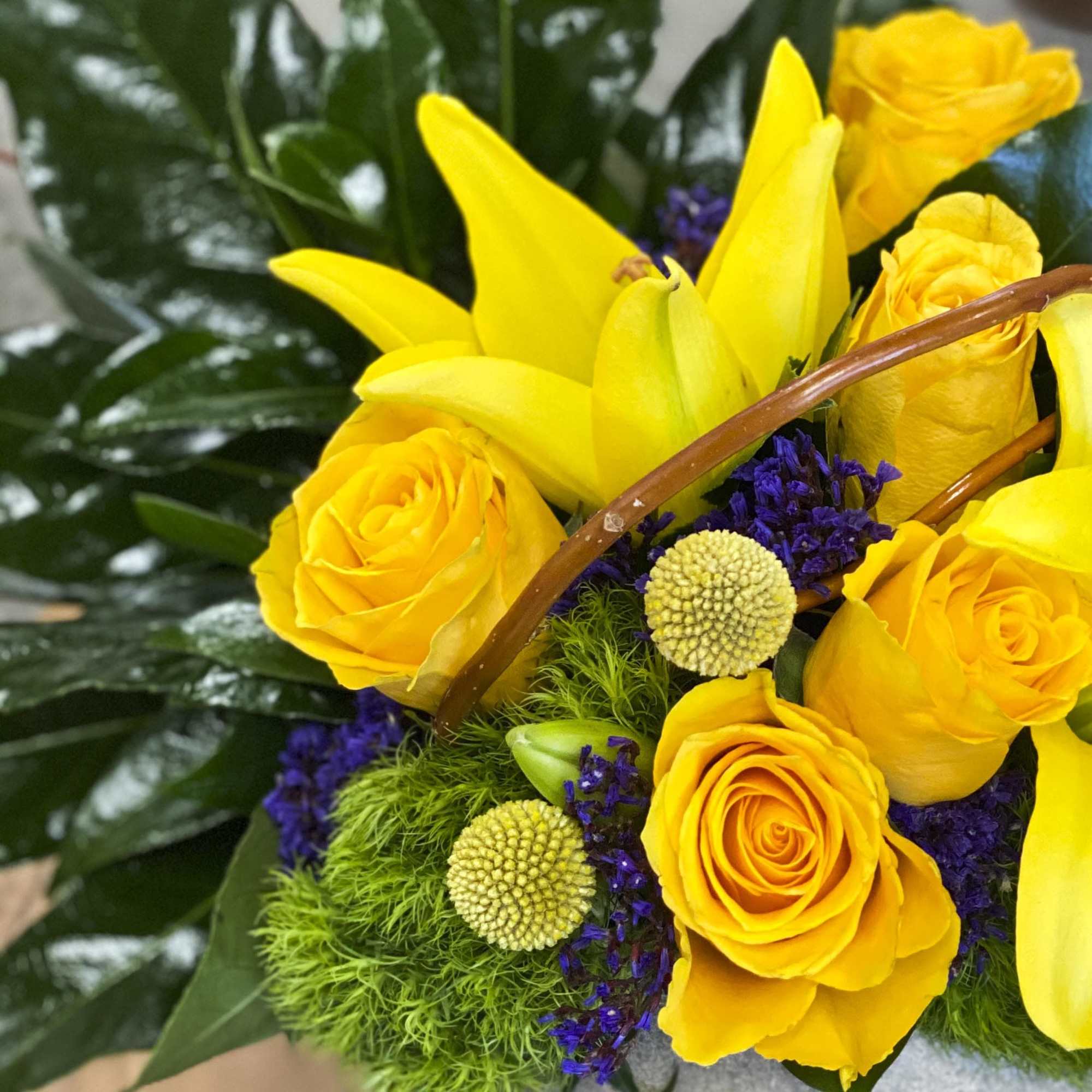 Yellow roses and lilies with purple accents in a bouquet