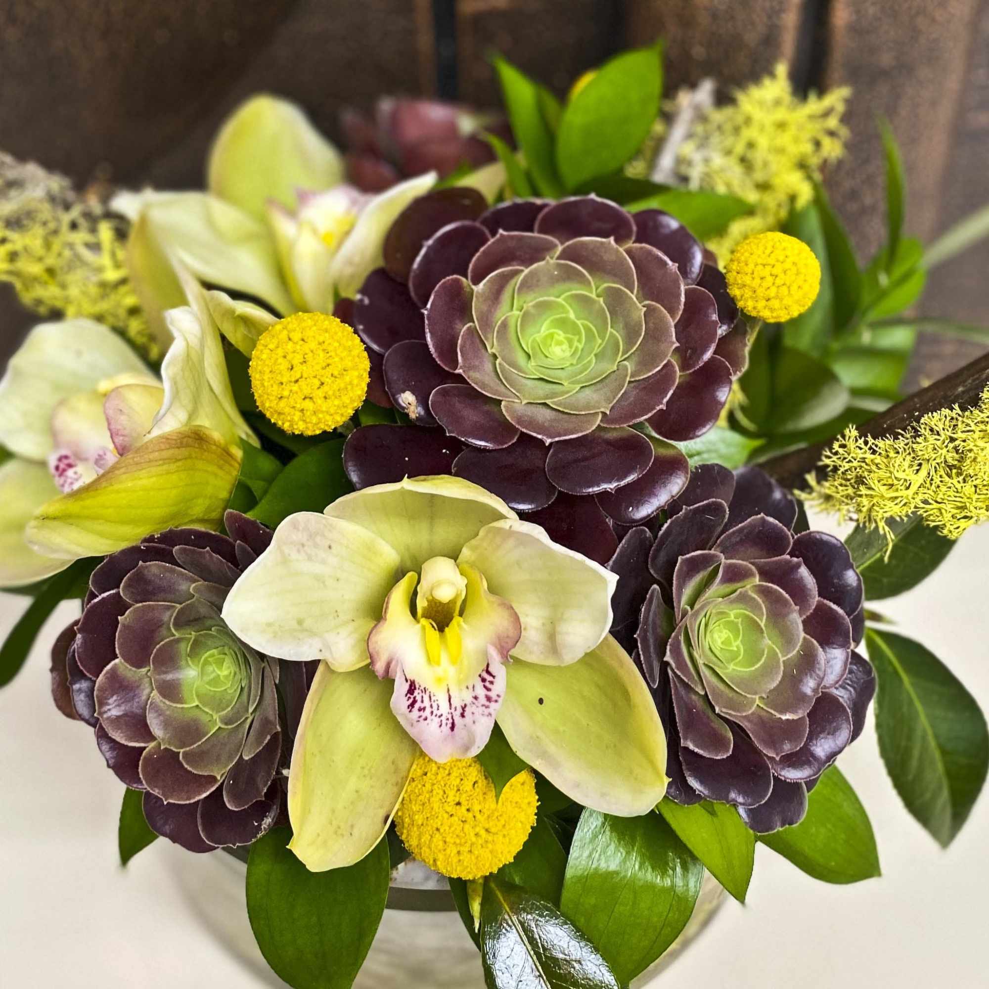 Bouquet with pale orchids, purple succulents, and yellow pom-pom flowers