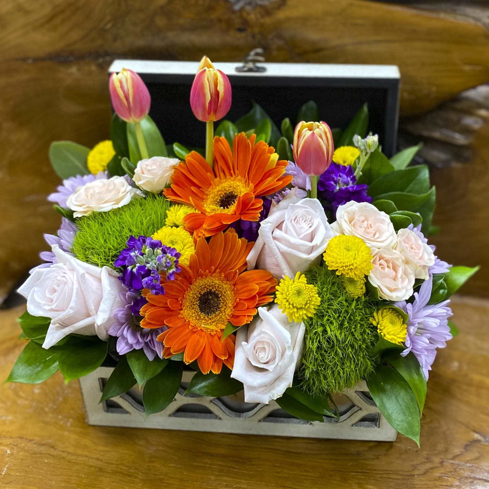 Mixed bouquet with orange gerbera daisies, pink tulips, and pale roses in a box