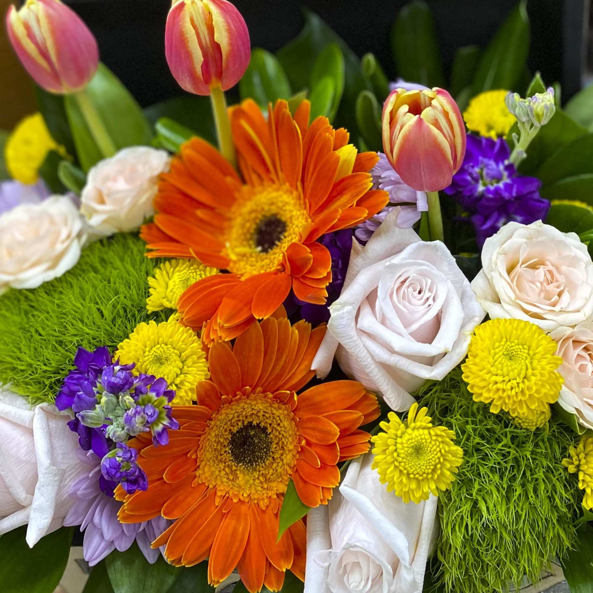 Mixed bouquet with orange gerbera daisies, pink tulips, and pale roses