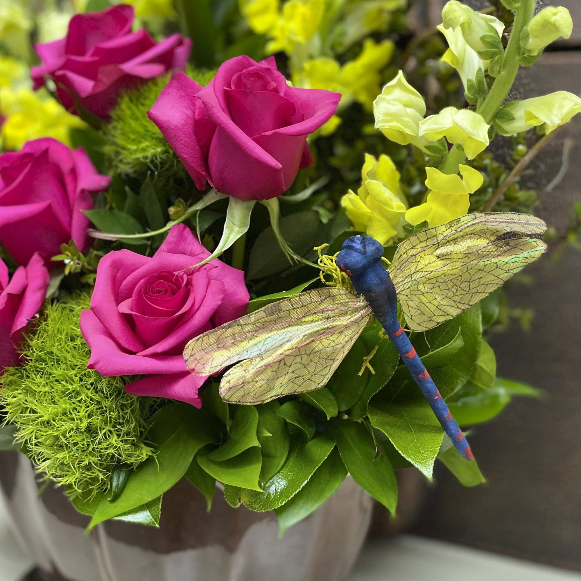 Pink roses with yellow snapdragons and a decorative dragonfly pick