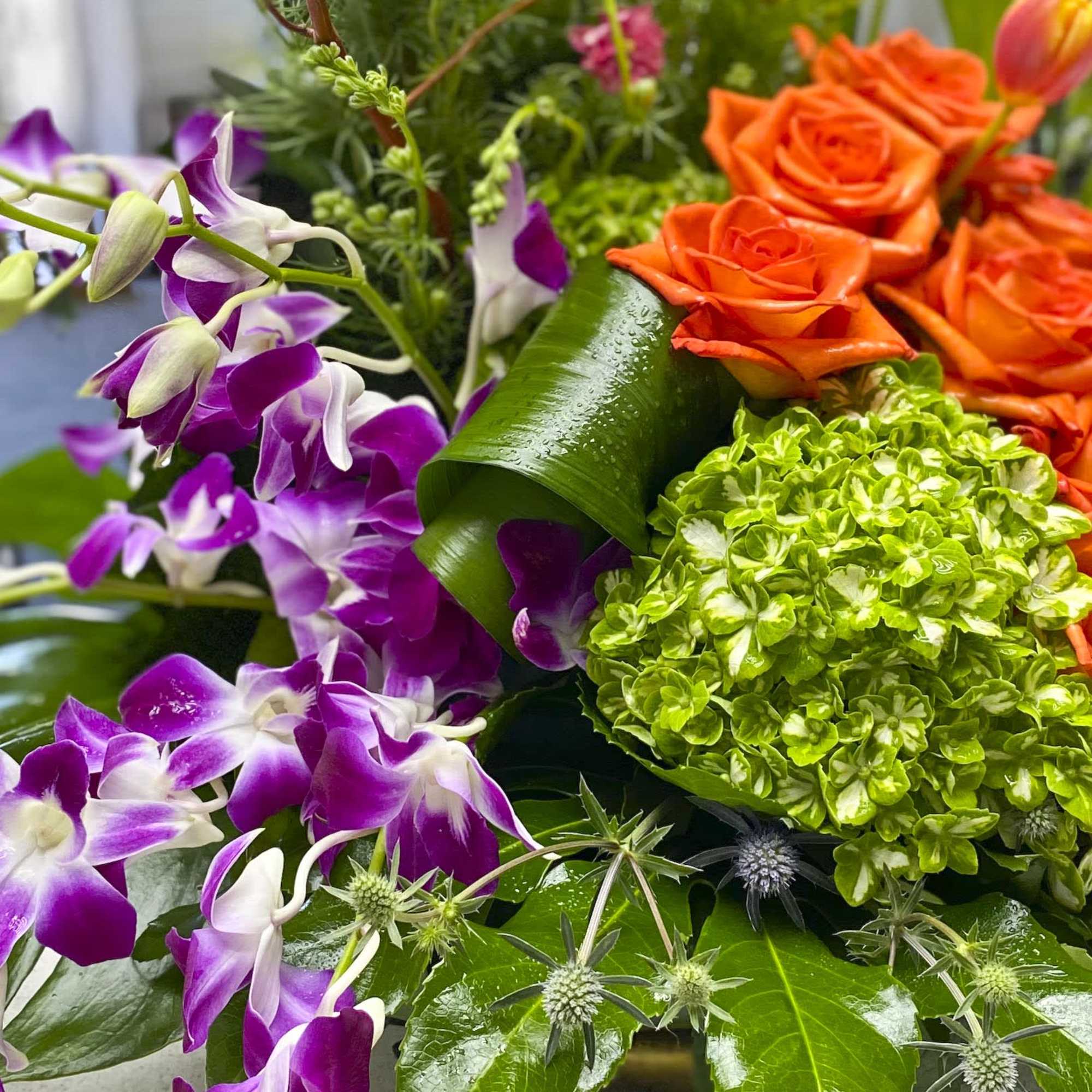 Bouquet of orange roses, purple orchids, and green hydrangea