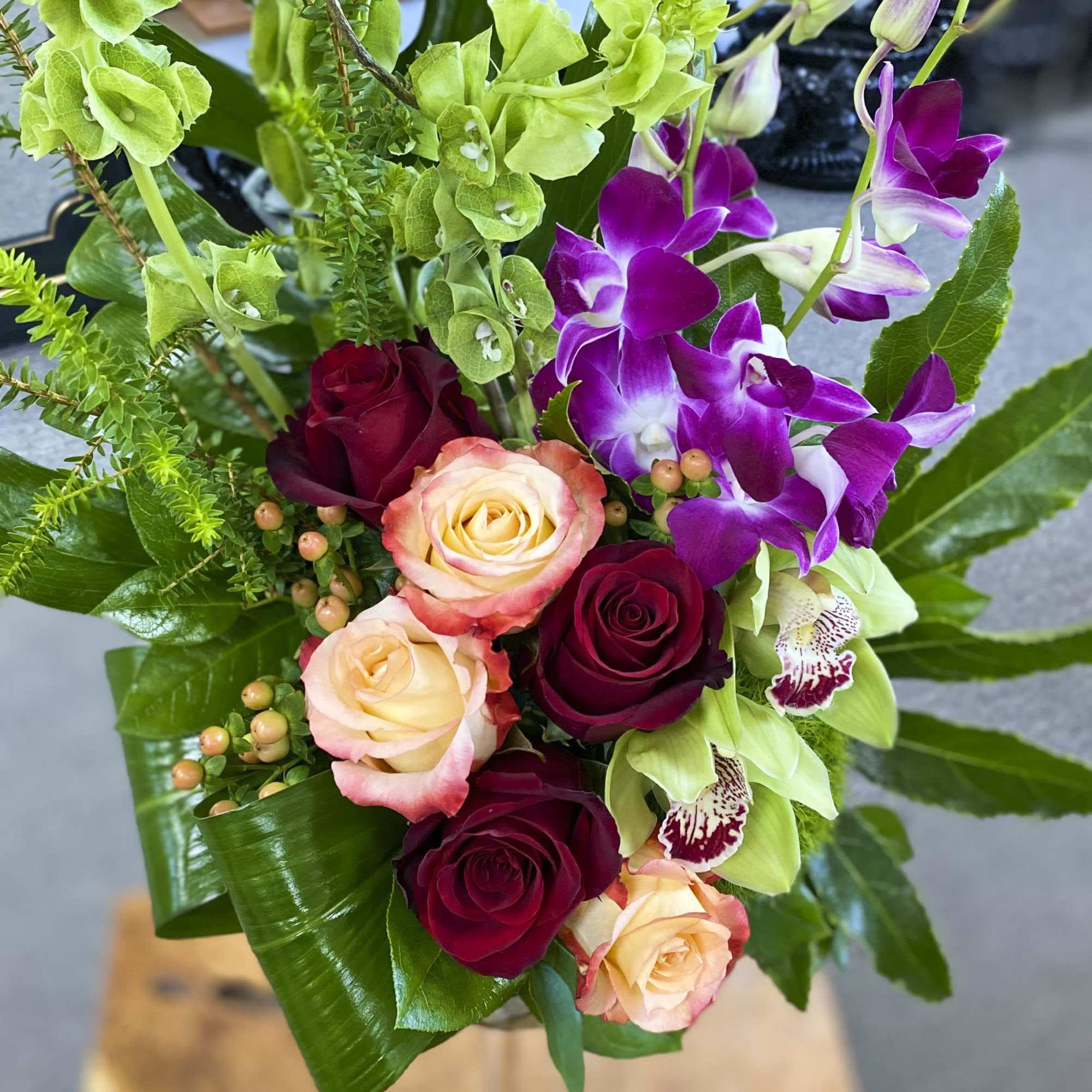 Bouquet of roses and purple orchids with green accents