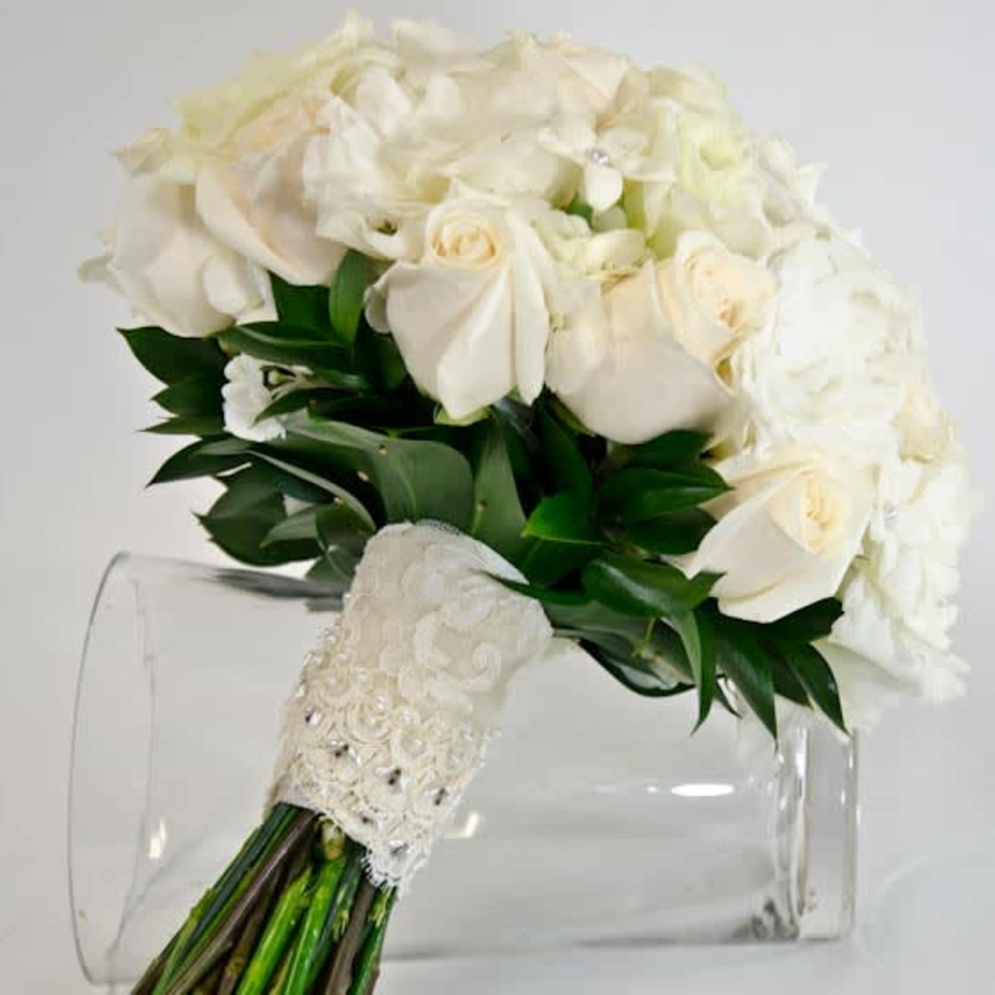 White rose bouquet with hydrangea and greenery in a clear vase