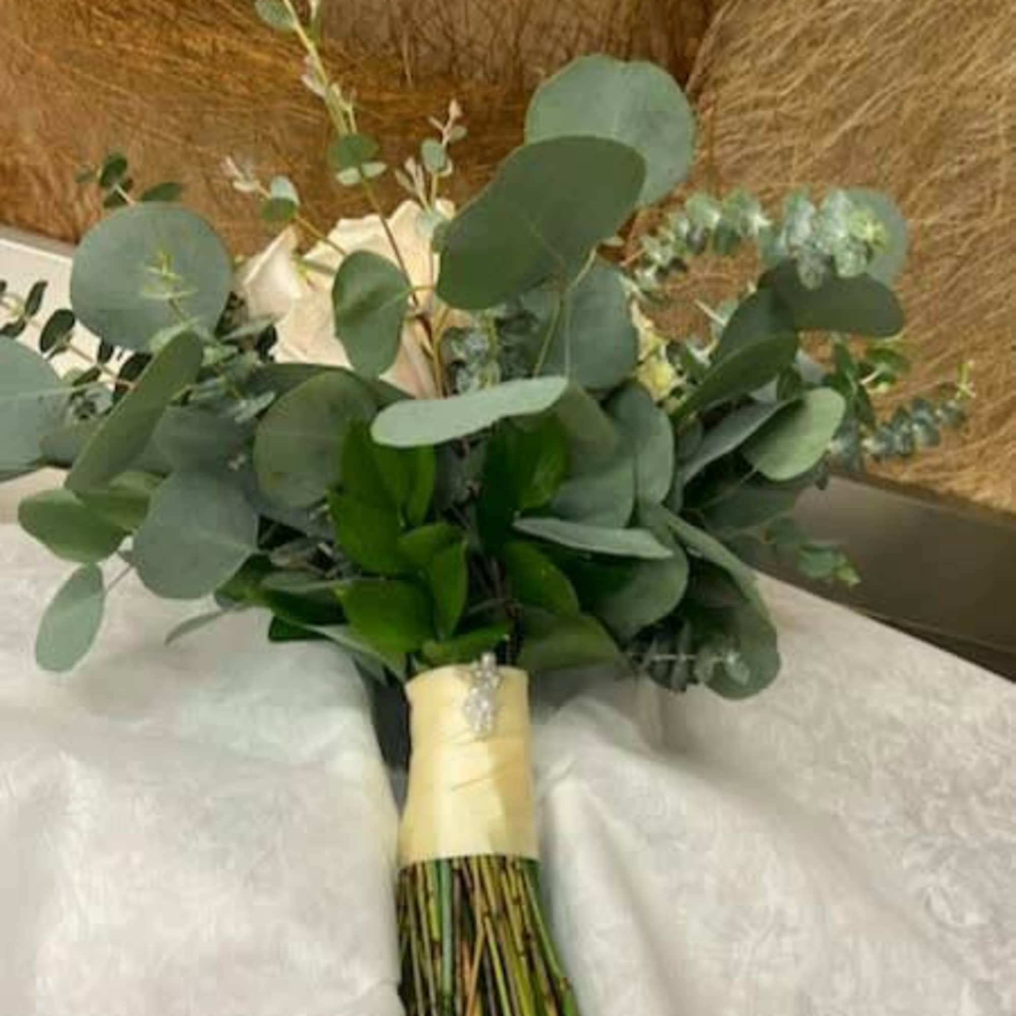 Bouquet of white roses and eucalyptus wrapped with pale ribbon