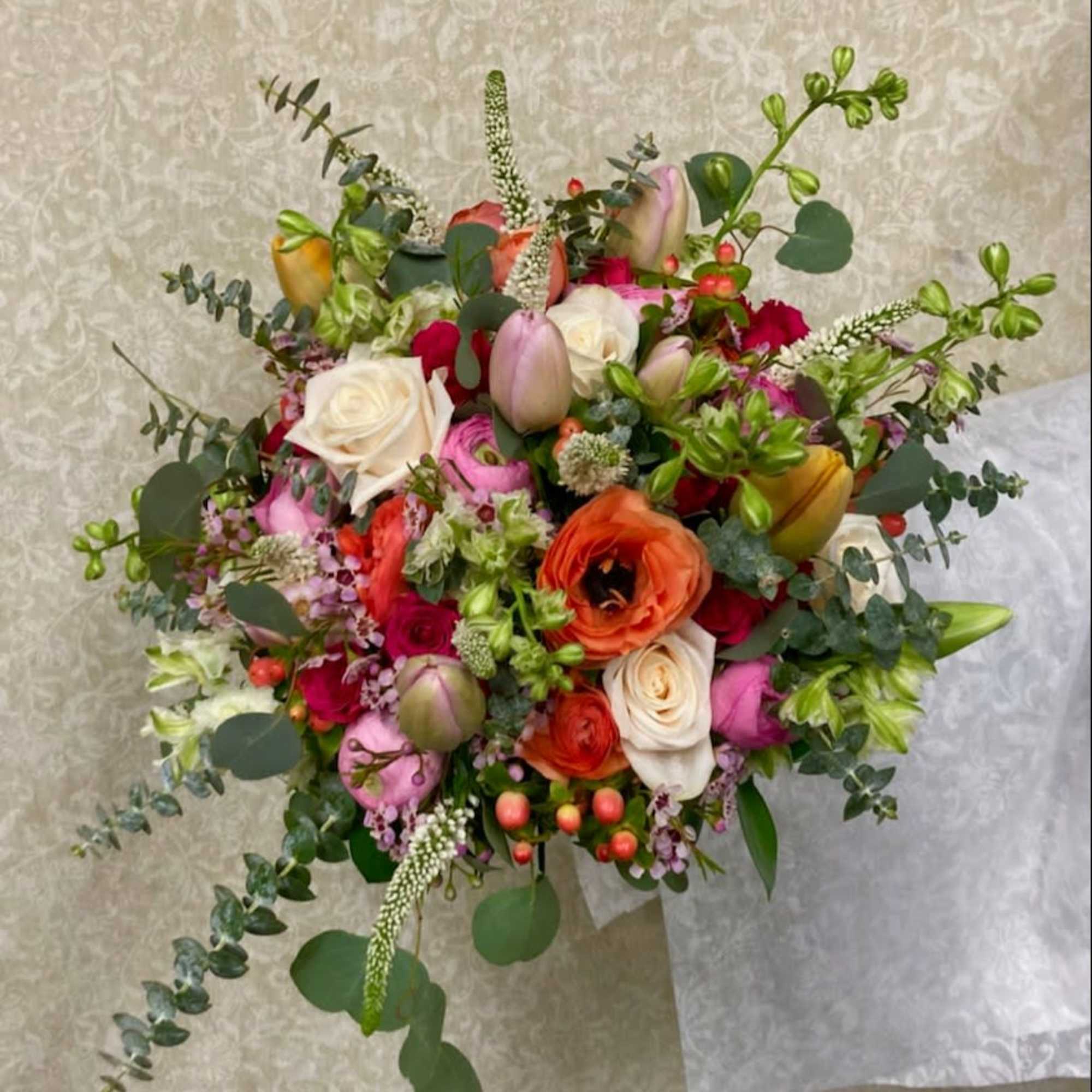 Mixed bouquet of roses, ranunculus, and tulips with eucalyptus