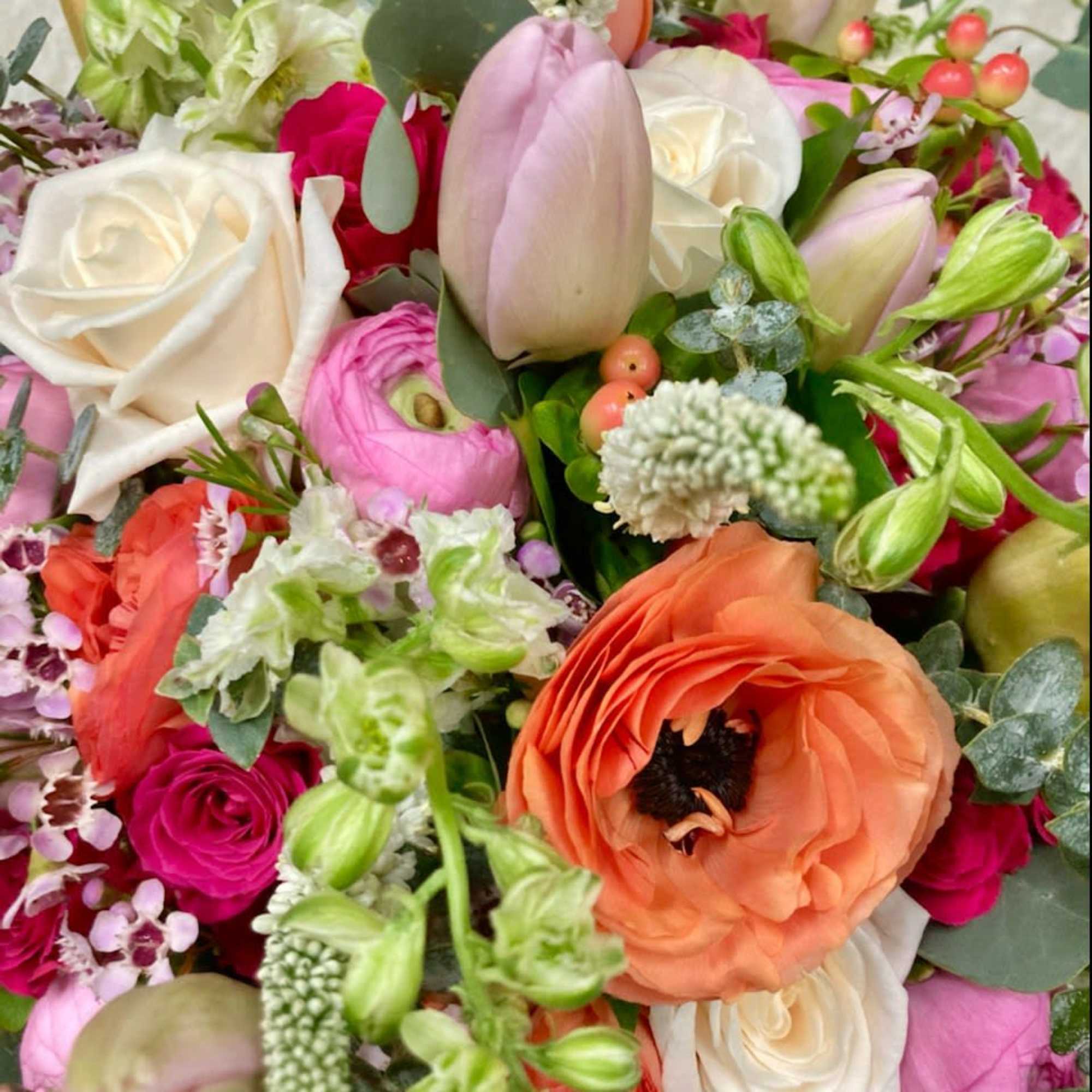 Mixed bouquet with roses, tulips, and ranunculus in pink, white, and orange